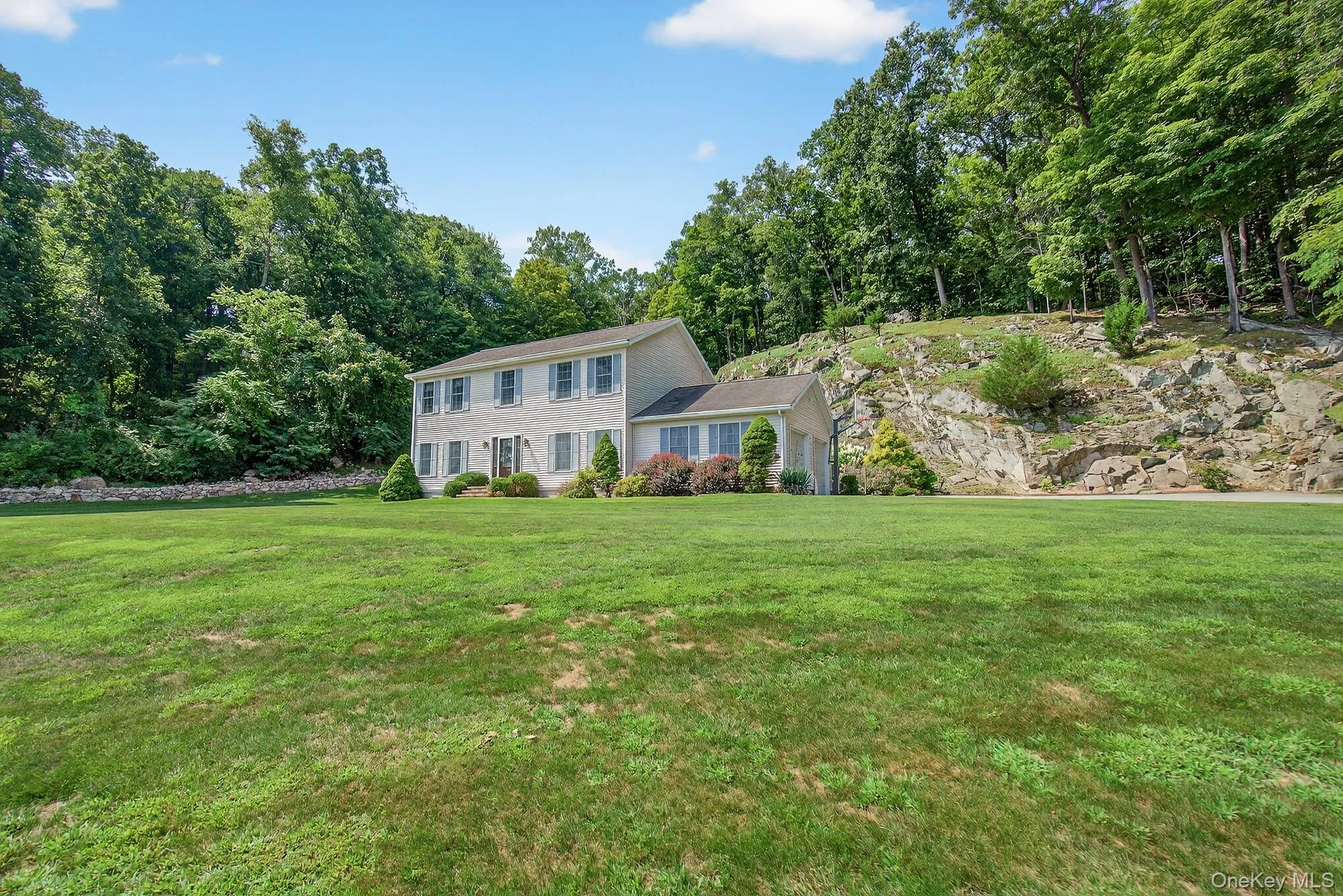 Colonial-style house with rock ledge behind home Colonial-style house with rock ledge behind home