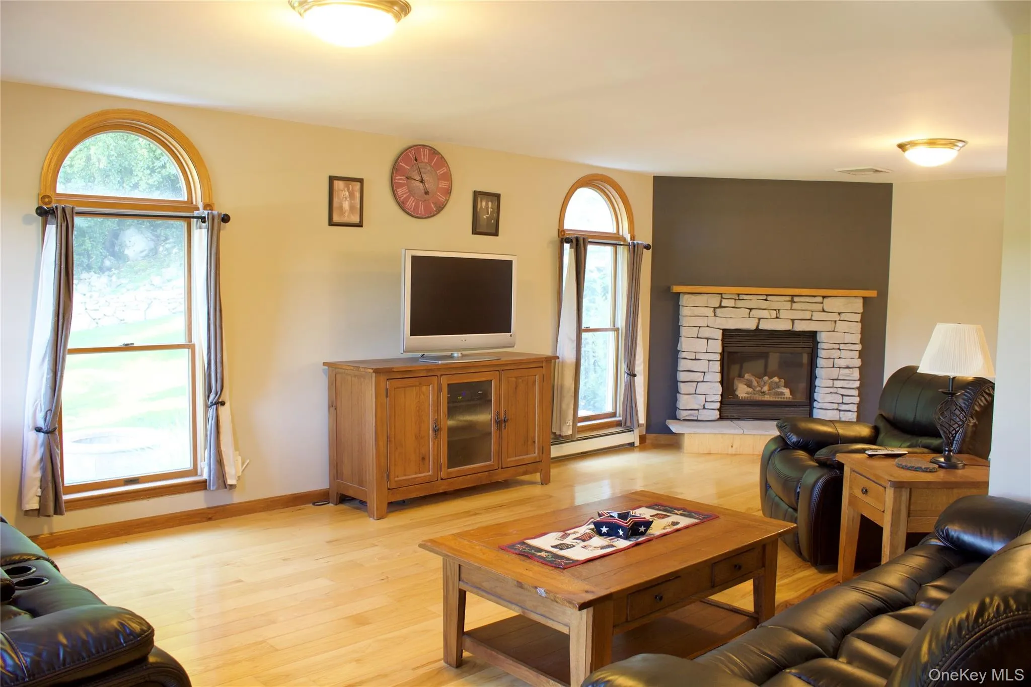 Living area featuring wood floors and a stone gas fireplace Living area featuring wood floors and a stone gas fireplace
