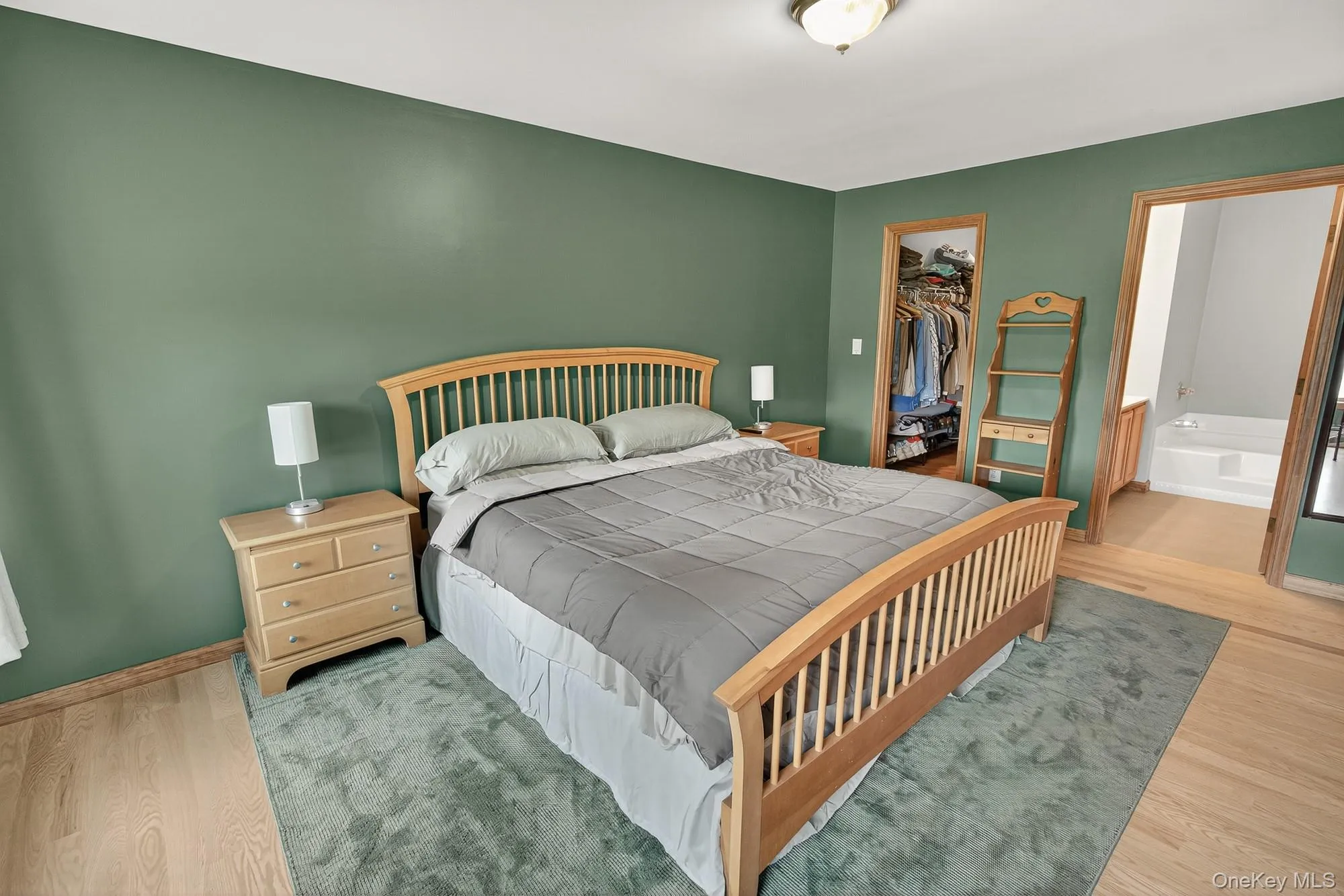 Bedroom featuring wood finished floors, a walk in closet, and ensuite bathroom Bedroom featuring wood finished floors, a walk in closet, and ensuite bathroom