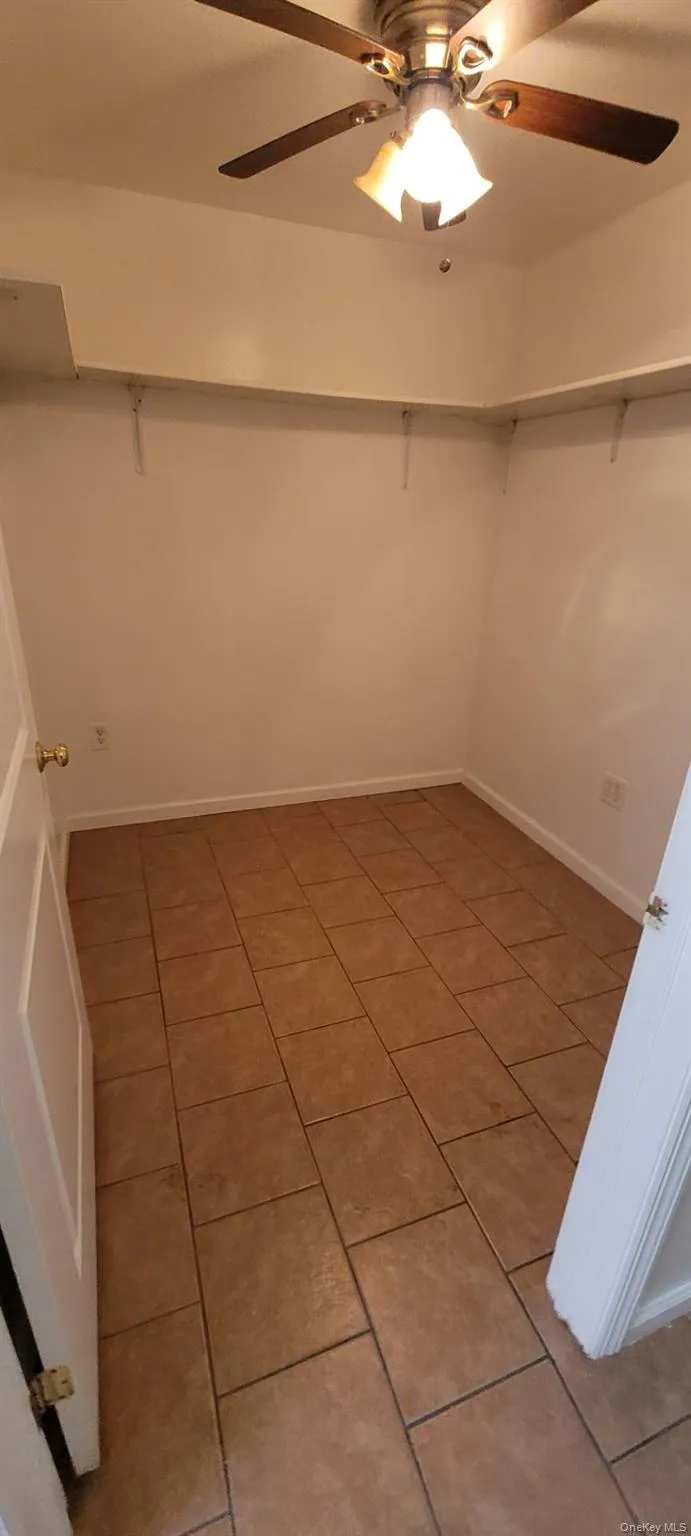 Spacious closet with ceiling fan and light tile patterned floors Spacious closet with ceiling fan and light tile patterned floors