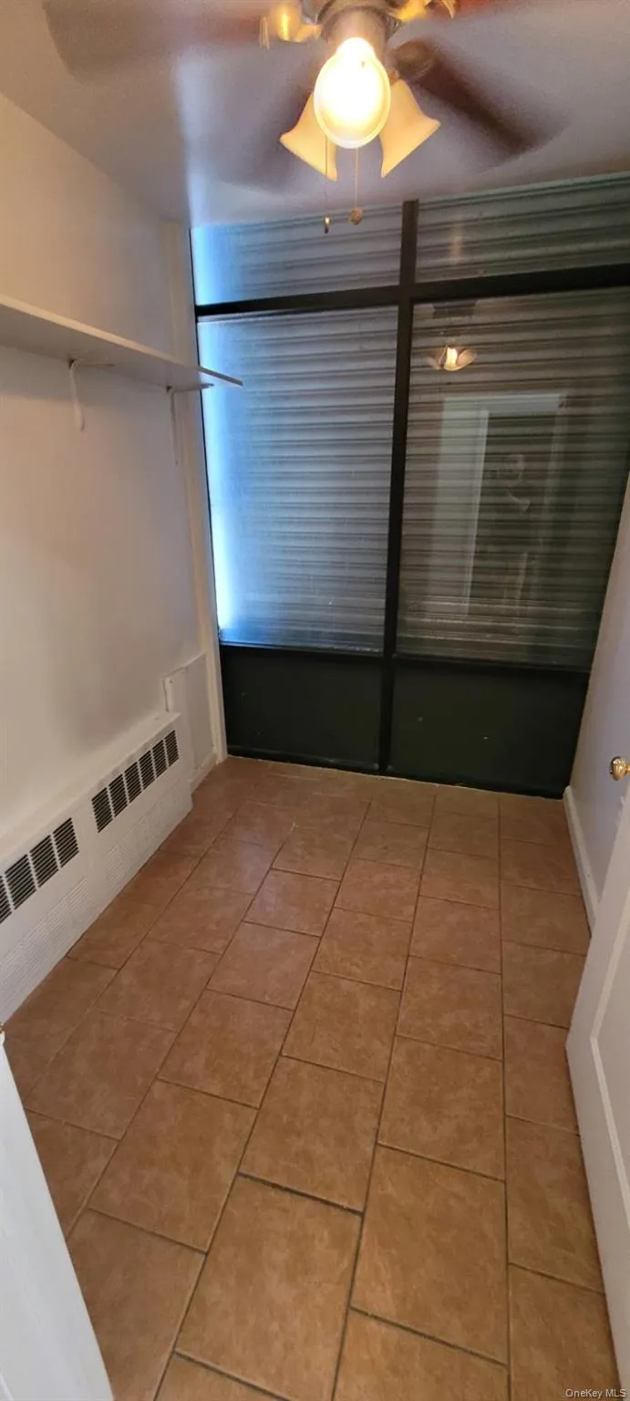 Spare room with radiator heating unit, light tile patterned floors, and ceiling fan Spare room with radiator heating unit, light tile patterned floors, and ceiling fan