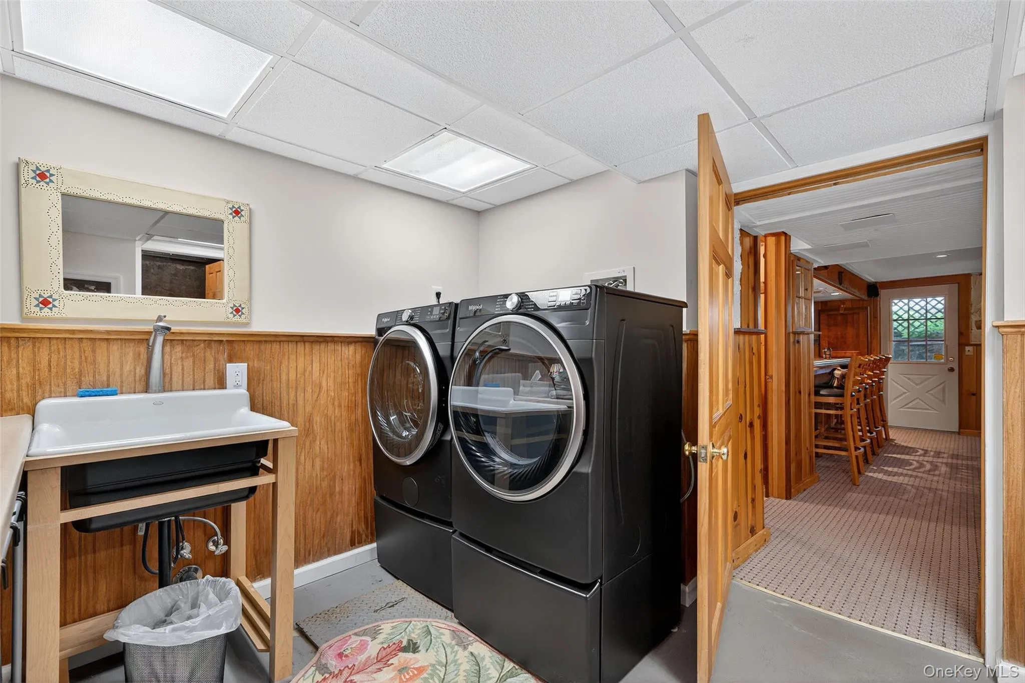 Washroom featuring wood walls, a wainscoted wall, and washer and clothes dryer Washroom featuring wood walls, a wainscoted wall, and washer and clothes dryer
