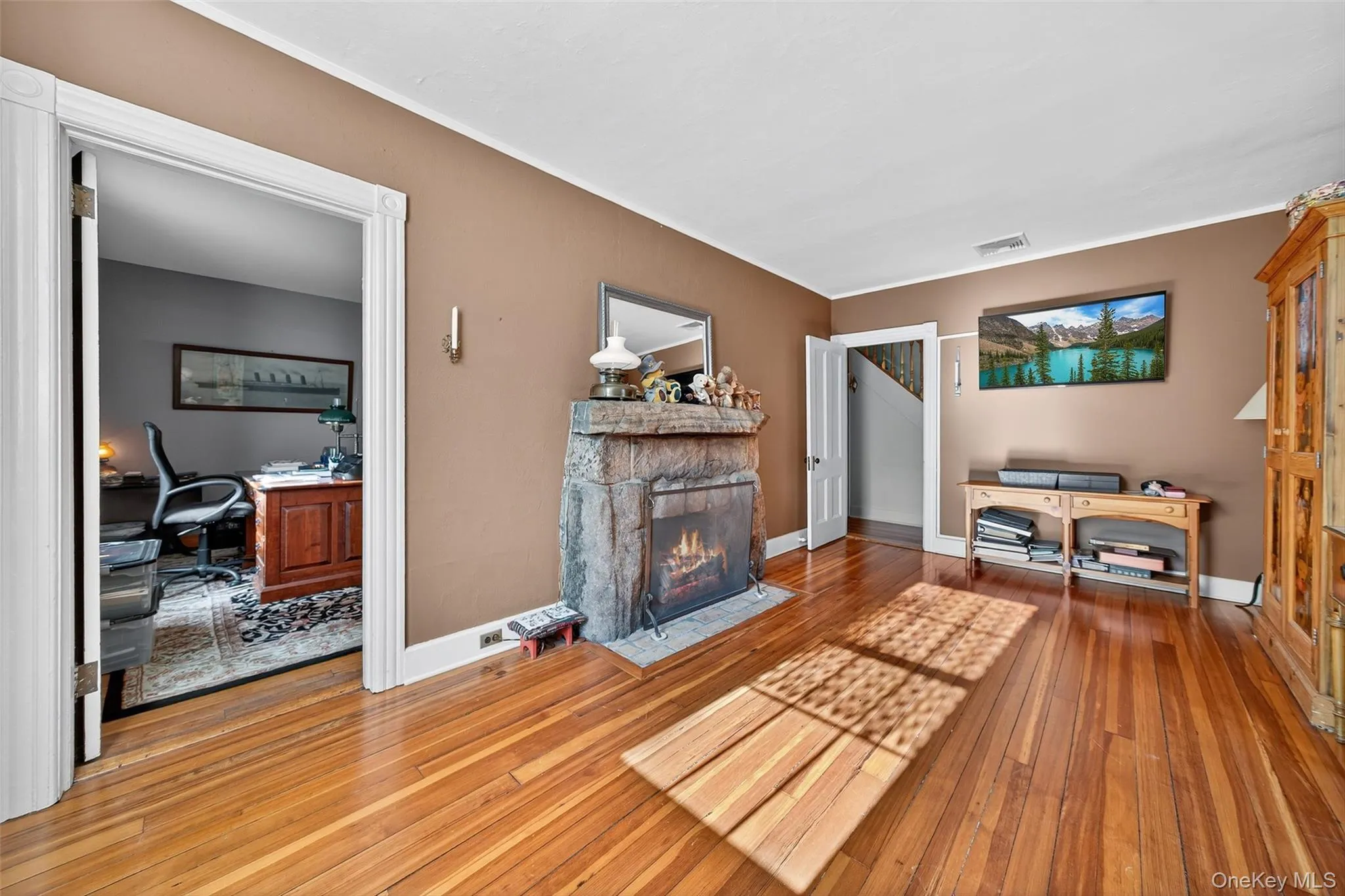 Living room with a desk, wood-type flooring, a fireplace, and crown molding Living room with a desk, wood-type flooring, a fireplace, and crown molding