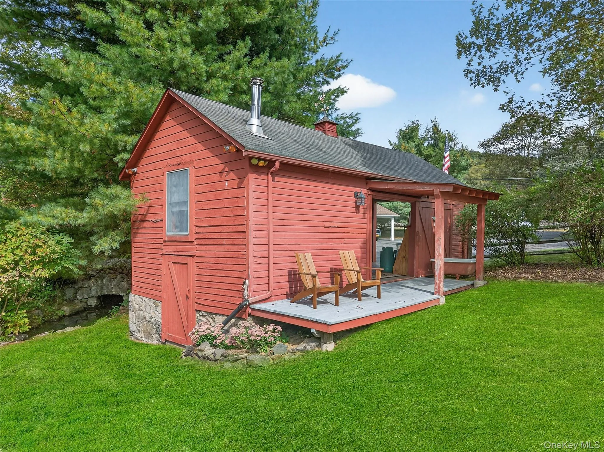 Back of property featuring a chimney, a lawn, a wooden deck, and a shingled roof Back of property featuring a chimney, a lawn, a wooden deck, and a shingled roof
