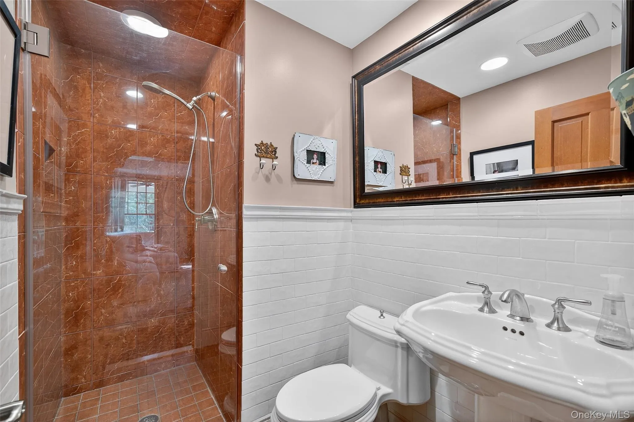 Main Floor Full bathroom featuring a stall shower, tile walls, and a wainscoted wall Main Floor Full bathroom featuring a stall shower, tile walls, and a wainscoted wall