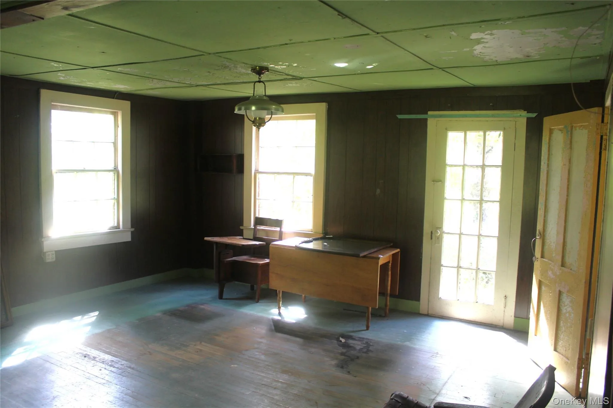 Office space with plenty of natural light, wood-type flooring, a paneled ceiling, and wooden walls Office space with plenty of natural light, wood-type flooring, a paneled ceiling, and wooden walls