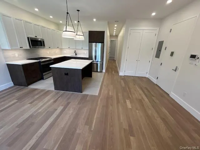 Kitchen featuring stainless steel appliances, dark brown cabinets, tasteful backsplash, a center island, and recessed lighting Kitchen featuring stainless steel appliances, dark brown cabinets, tasteful backsplash, a center island, and recessed lighting