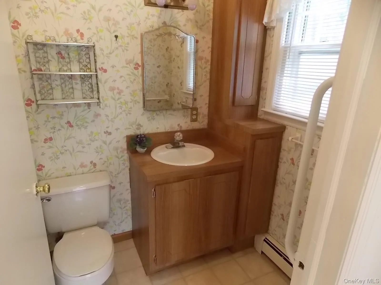 Bathroom featuring wallpapered walls, vanity, a baseboard heating unit, and light tile patterned floors Bathroom featuring wallpapered walls, vanity, a baseboard heating unit, and light tile patterned floors