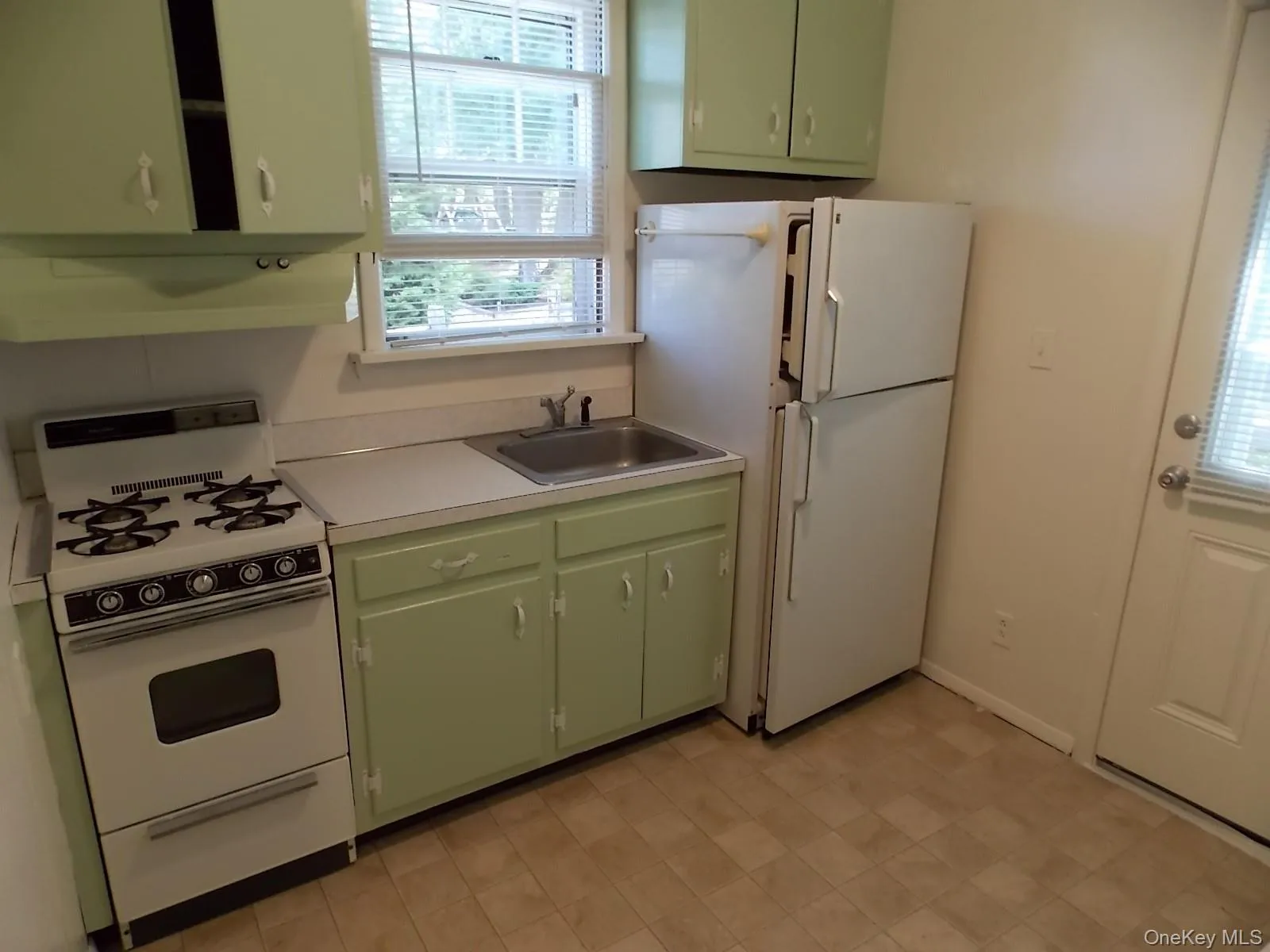 Kitchen featuring green cabinets, white appliances, light countertops, and under cabinet range hood Kitchen featuring green cabinets, white appliances, light countertops, and under cabinet range hood