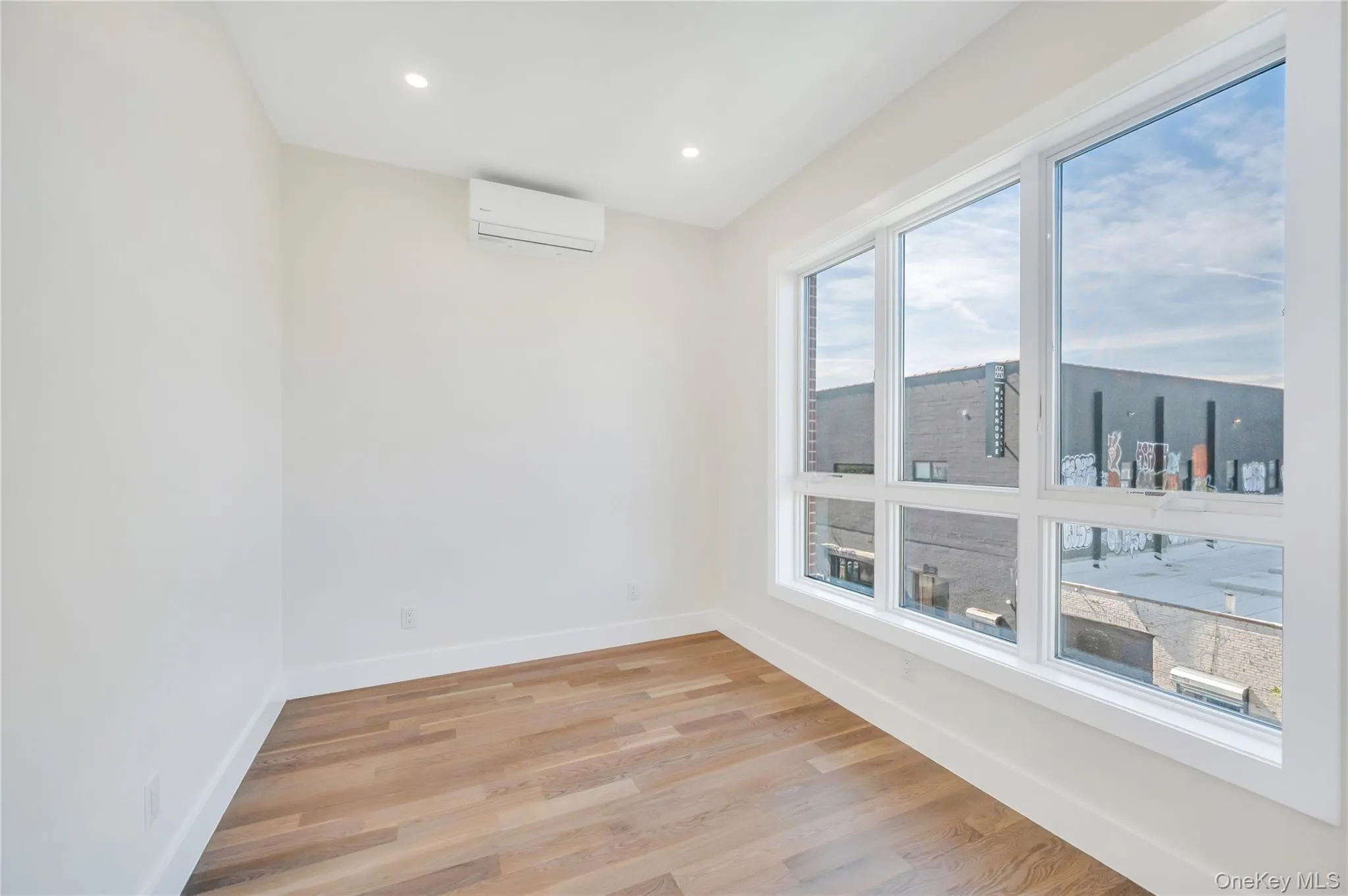 Spare room featuring light wood finished floors, recessed lighting, and a wall mounted air conditioner Spare room featuring light wood finished floors, recessed lighting, and a wall mounted air conditioner