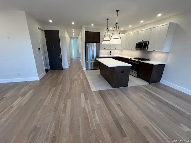Kitchen featuring open floor plan, dark brown cabinetry, appliances with stainless steel finishes, white cabinetry, and tasteful backsplash Kitchen featuring open floor plan, dark brown cabinetry, appliances with stainless steel finishes, white cabinetry, and tasteful backsplash