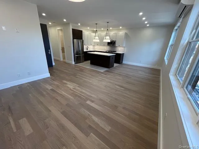 Kitchen featuring open floor plan, appliances with stainless steel finishes, recessed lighting, an AC wall unit, and dark wood finished floors Kitchen featuring open floor plan, appliances with stainless steel finishes, recessed lighting, an AC wall unit, and dark wood finished floors