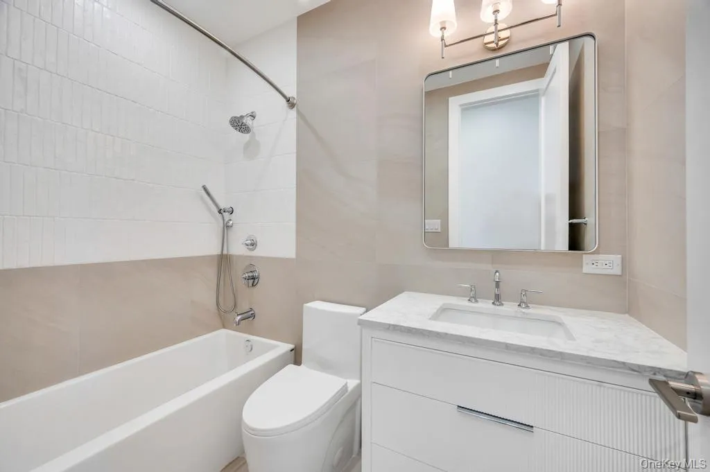 Full bathroom with bathtub / shower combination, vanity, and tile walls Full bathroom with bathtub / shower combination, vanity, and tile walls