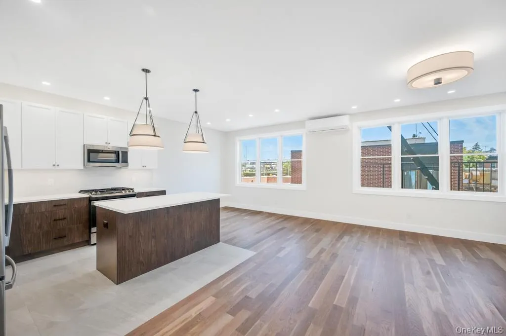 Kitchen featuring dark brown cabinetry, stainless steel appliances, decorative light fixtures, white cabinetry, and a center island Kitchen featuring dark brown cabinetry, stainless steel appliances, decorative light fixtures, white cabinetry, and a center island