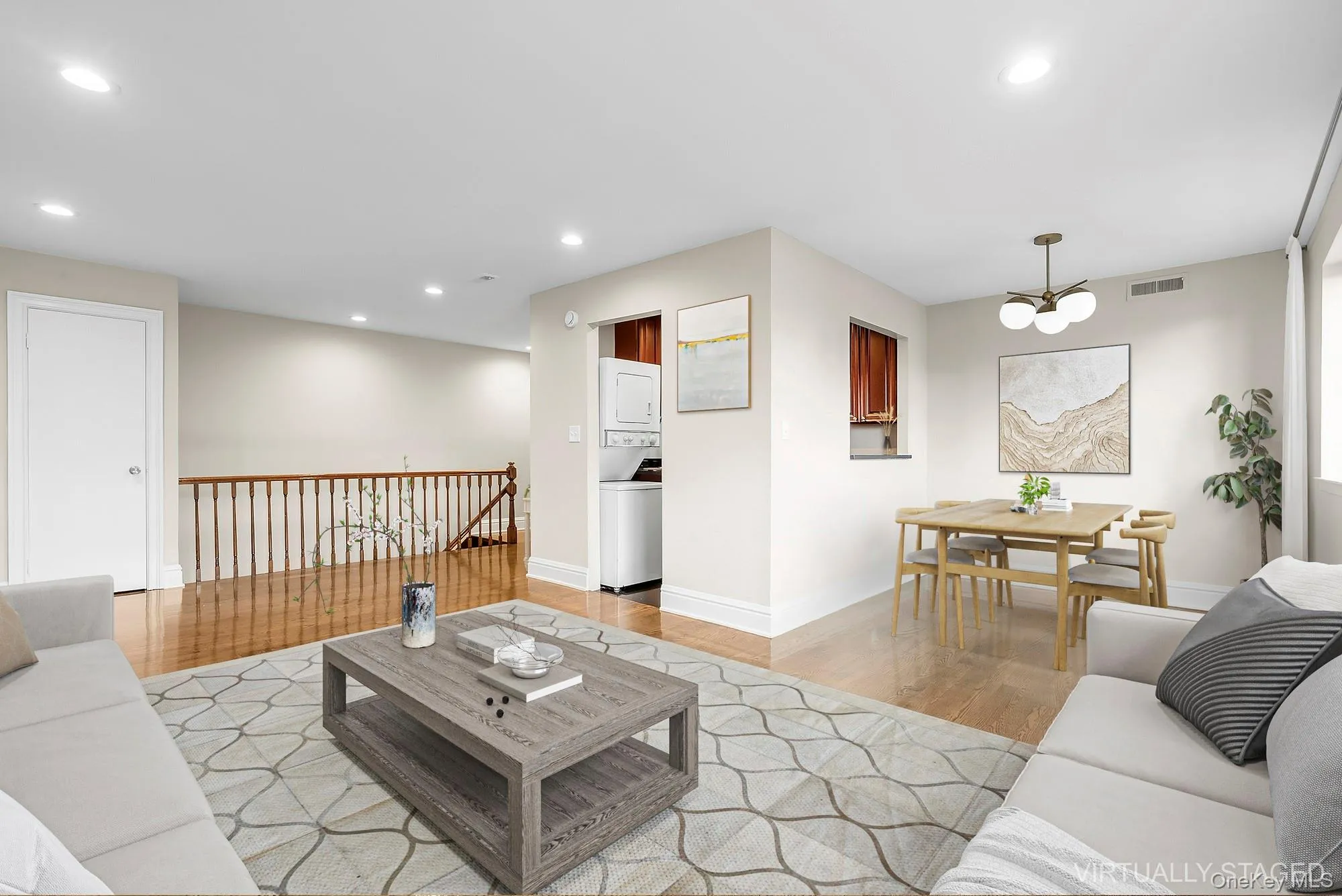 Living room with recessed lighting, light wood-type flooring, stacked washing machine and dryer, and a chandelier Living room with recessed lighting, light wood-type flooring, stacked washing machine and dryer, and a chandelier