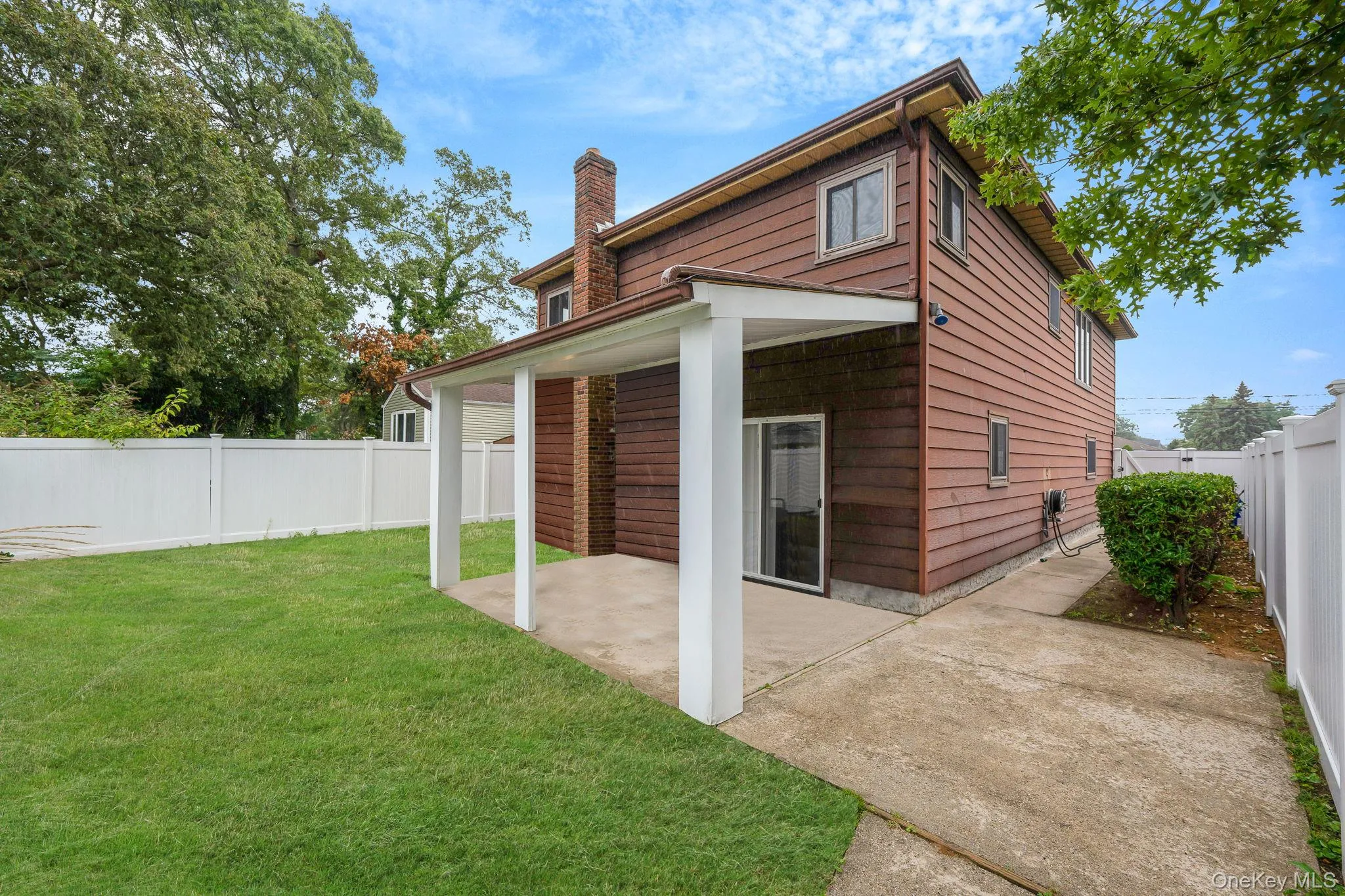 Back of house featuring a fenced backyard, a chimney, and a patio area Back of house featuring a fenced backyard, a chimney, and a patio area