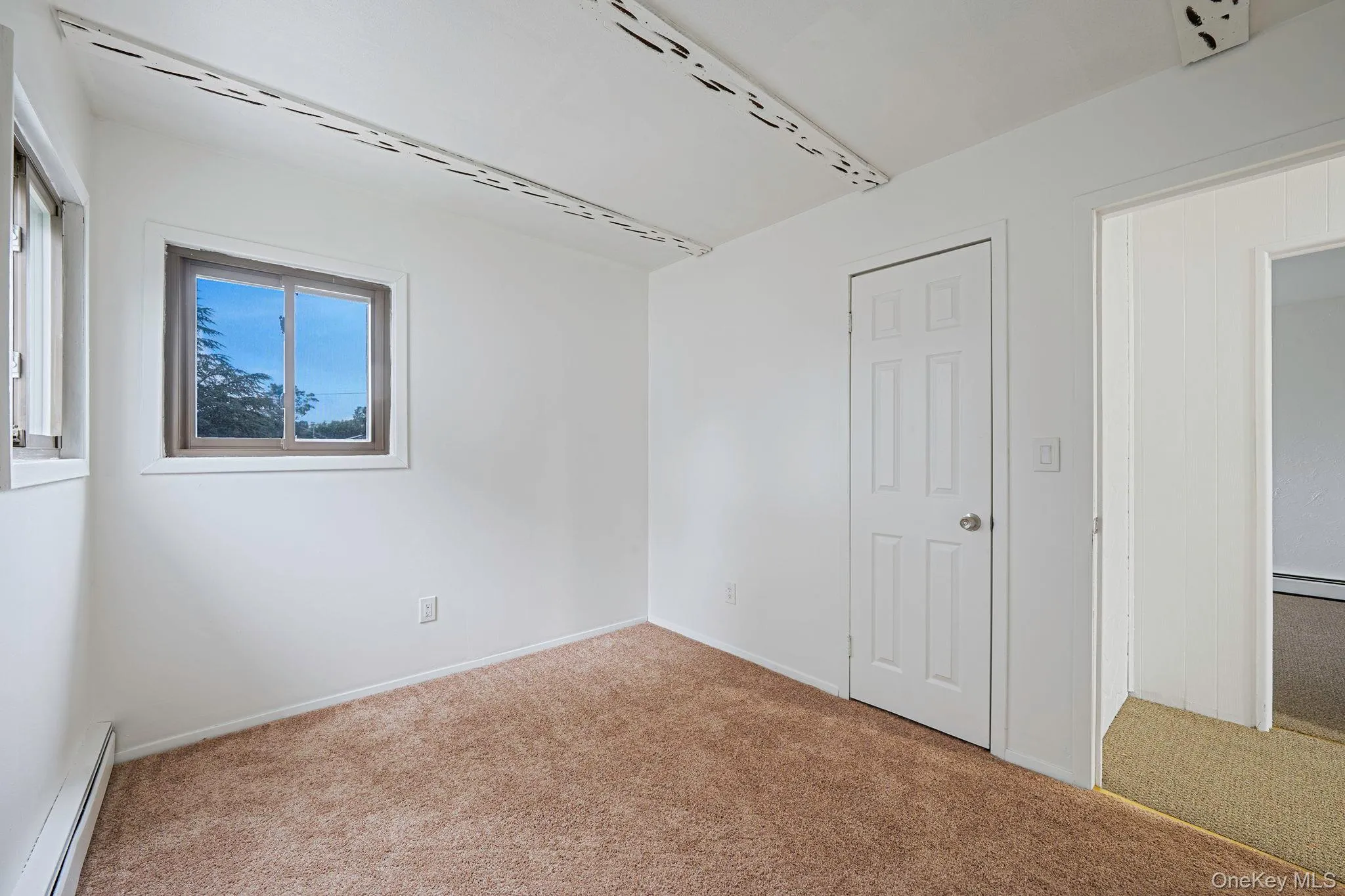 Unfurnished bedroom with a baseboard heating unit and carpet flooring Unfurnished bedroom with a baseboard heating unit and carpet flooring