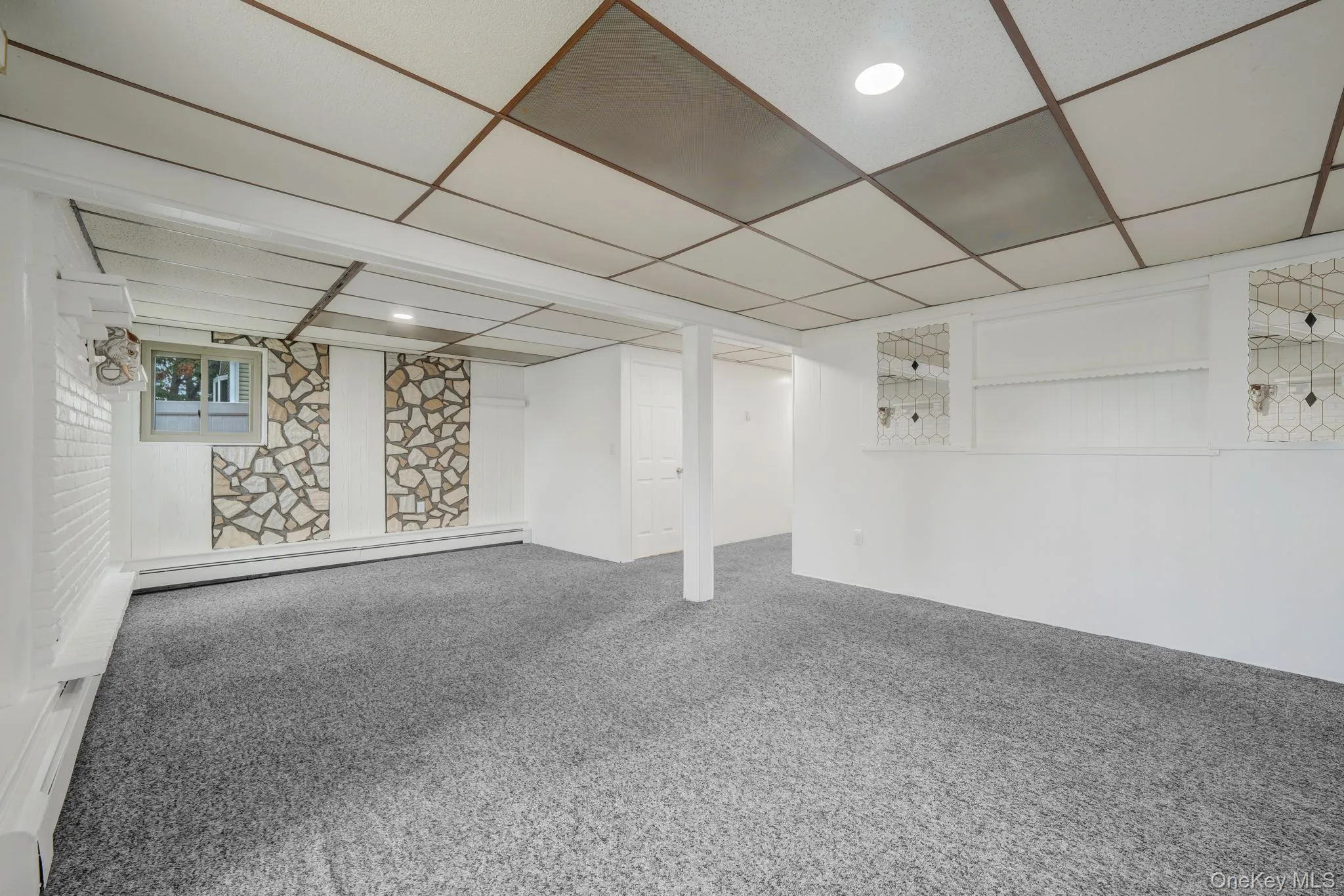 Finished basement featuring carpet, a drop ceiling, and baseboard heating Finished basement featuring carpet, a drop ceiling, and baseboard heating