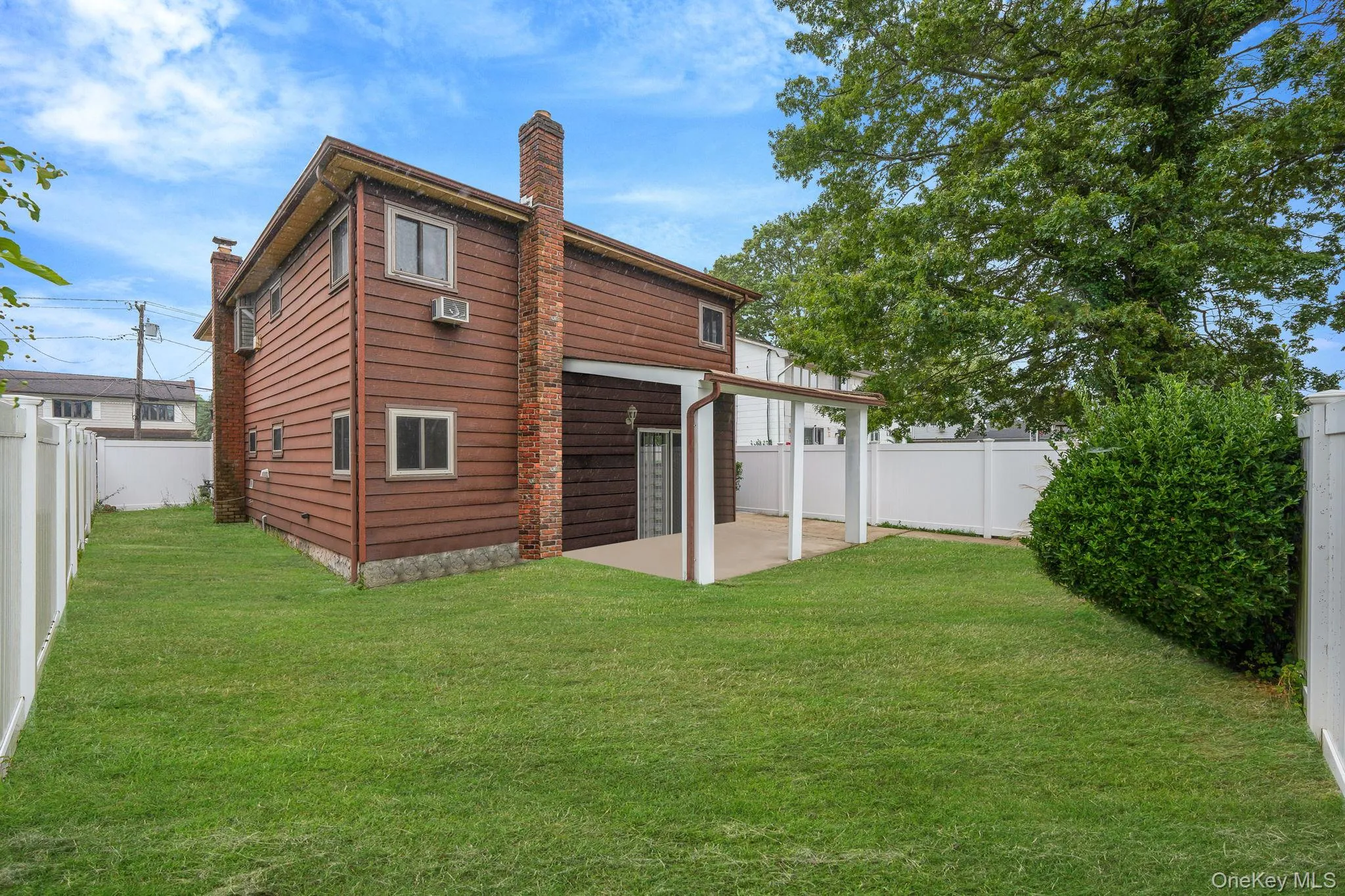 Rear view of house with a patio, a fenced backyard, and a chimney Rear view of house with a patio, a fenced backyard, and a chimney