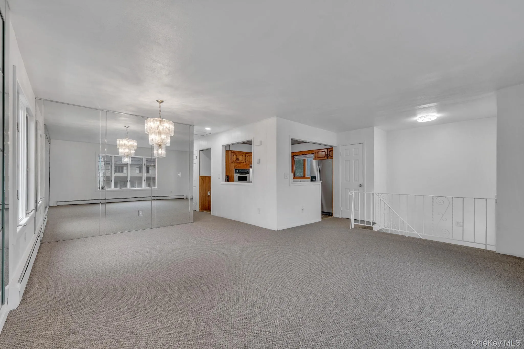 Unfurnished living room featuring carpet, a baseboard radiator, a chandelier, and a baseboard heating unit Unfurnished living room featuring carpet, a baseboard radiator, a chandelier, and a baseboard heating unit