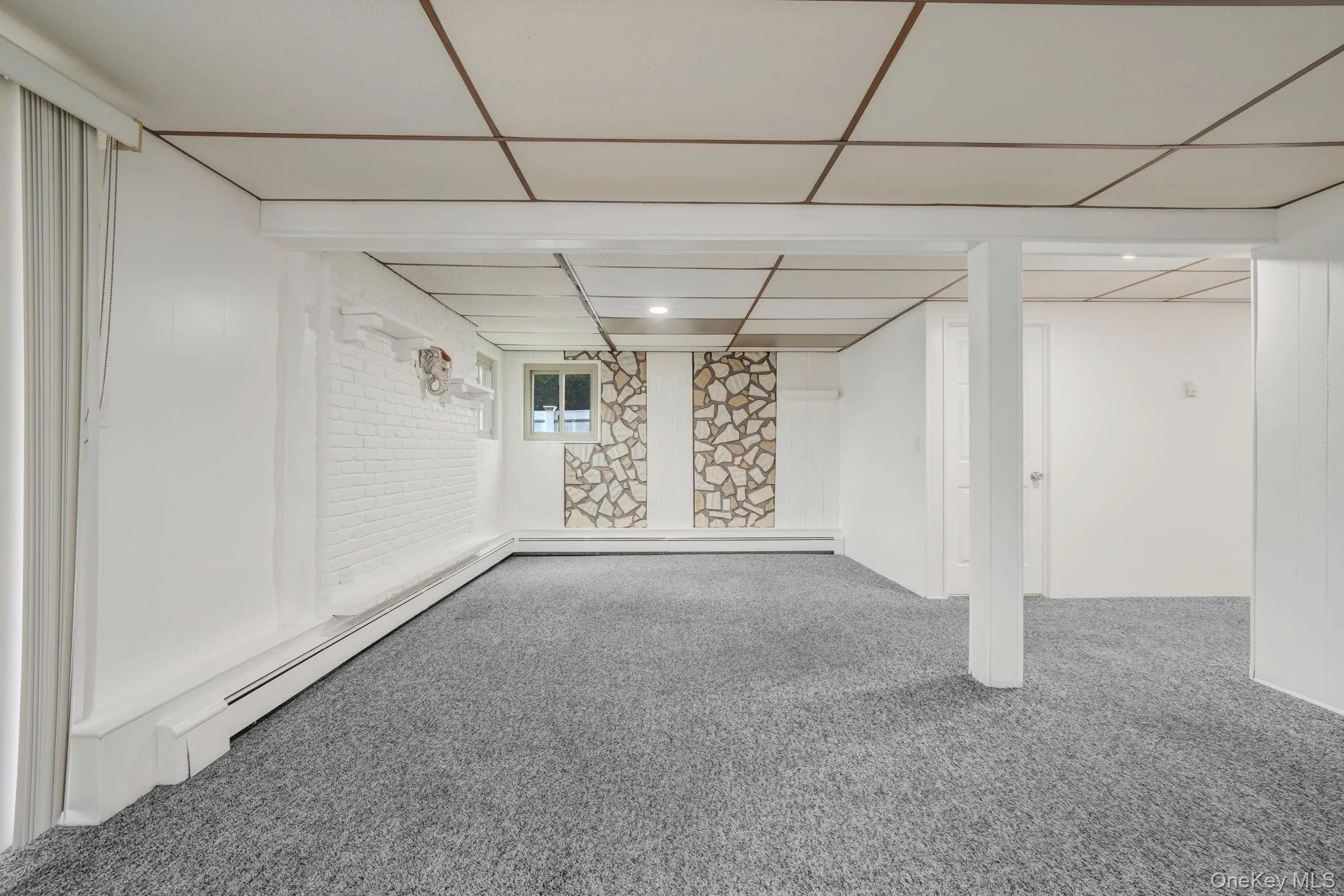 Below grade area featuring baseboard heating, carpet flooring, and a paneled ceiling Below grade area featuring baseboard heating, carpet flooring, and a paneled ceiling