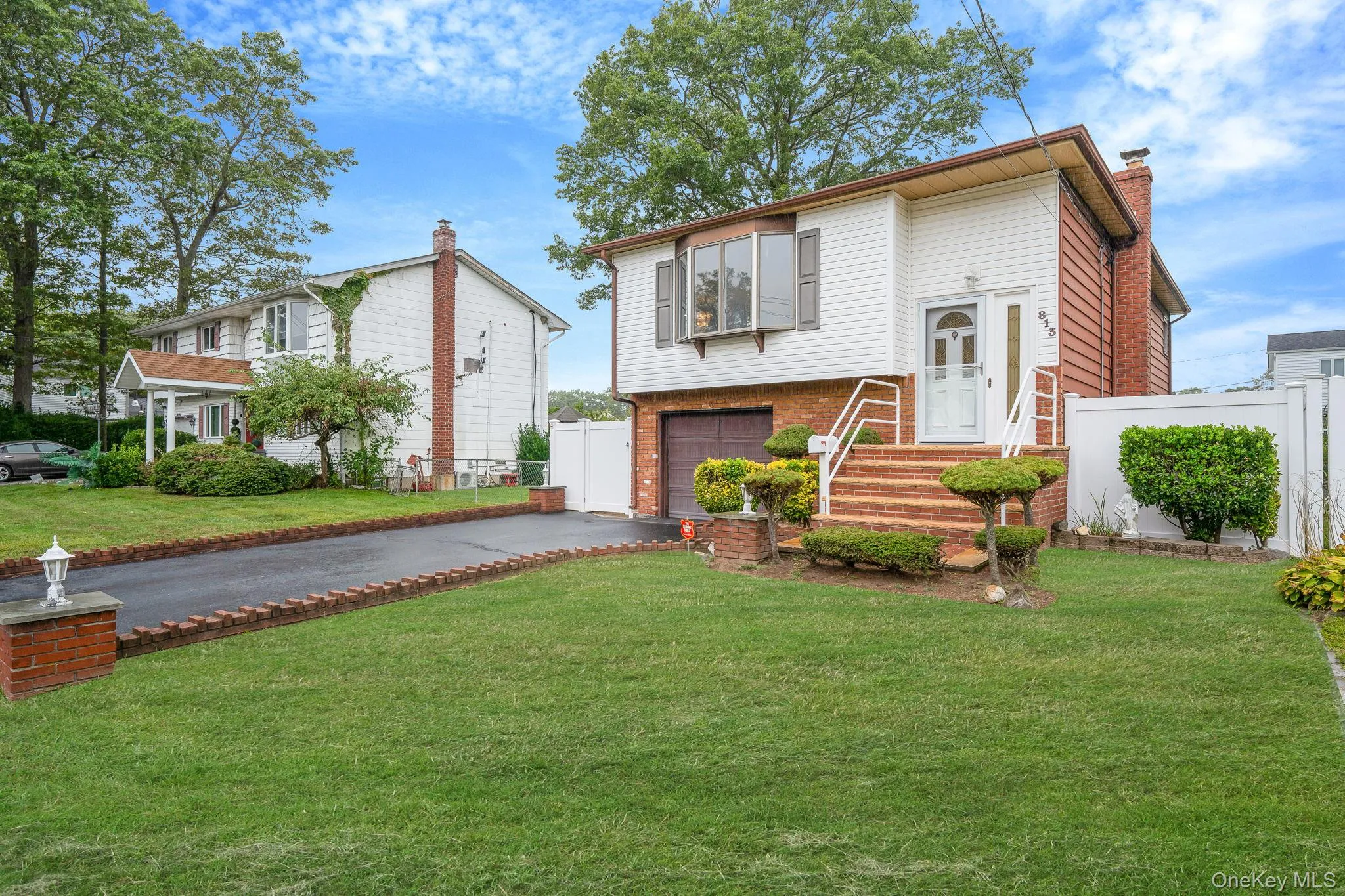 Bi-level home featuring driveway, a chimney, brick siding, and a garage Bi-level home featuring driveway, a chimney, brick siding, and a garage