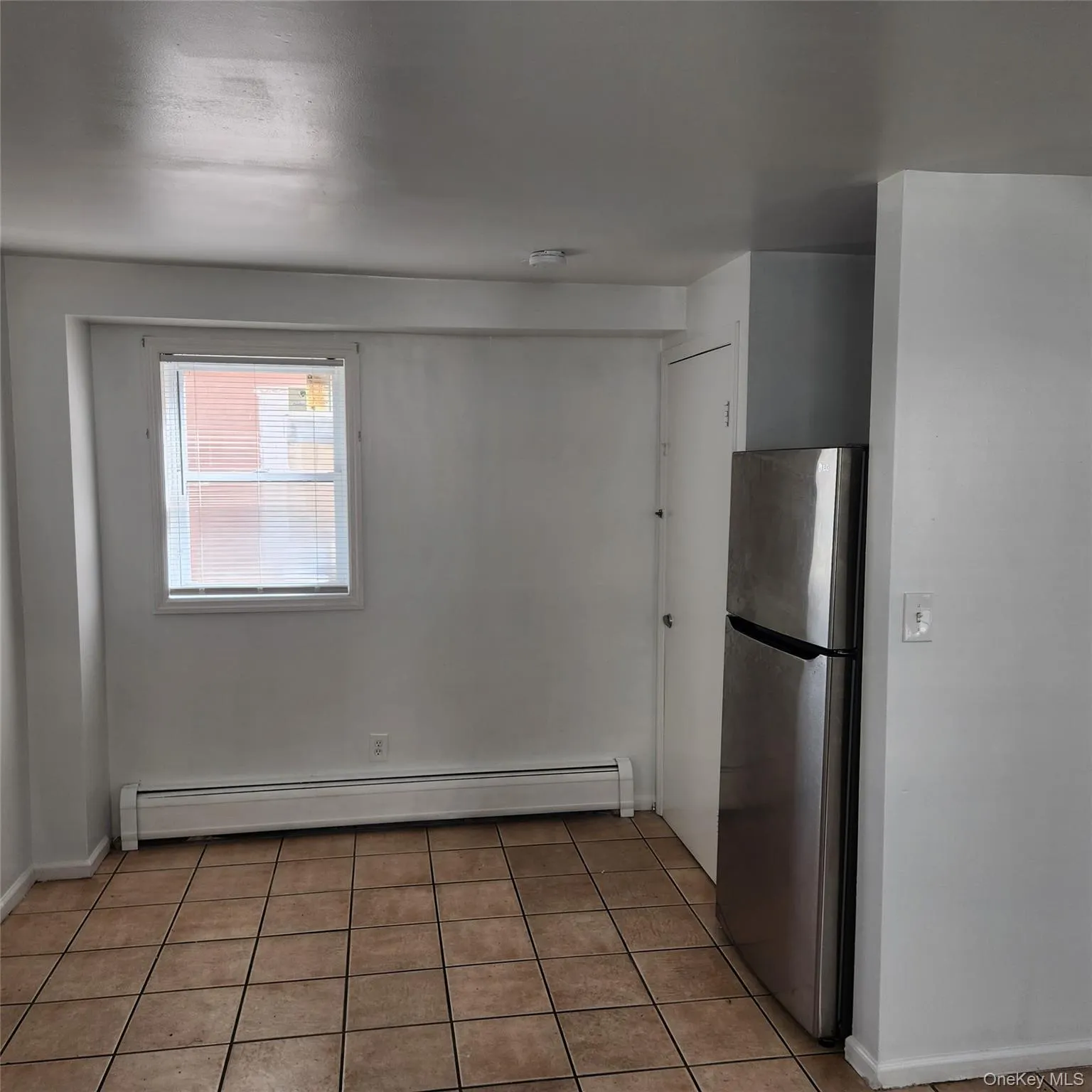 Kitchen with freestanding refrigerator, light tile patterned flooring, and a baseboard radiator Kitchen with freestanding refrigerator, light tile patterned flooring, and a baseboard radiator