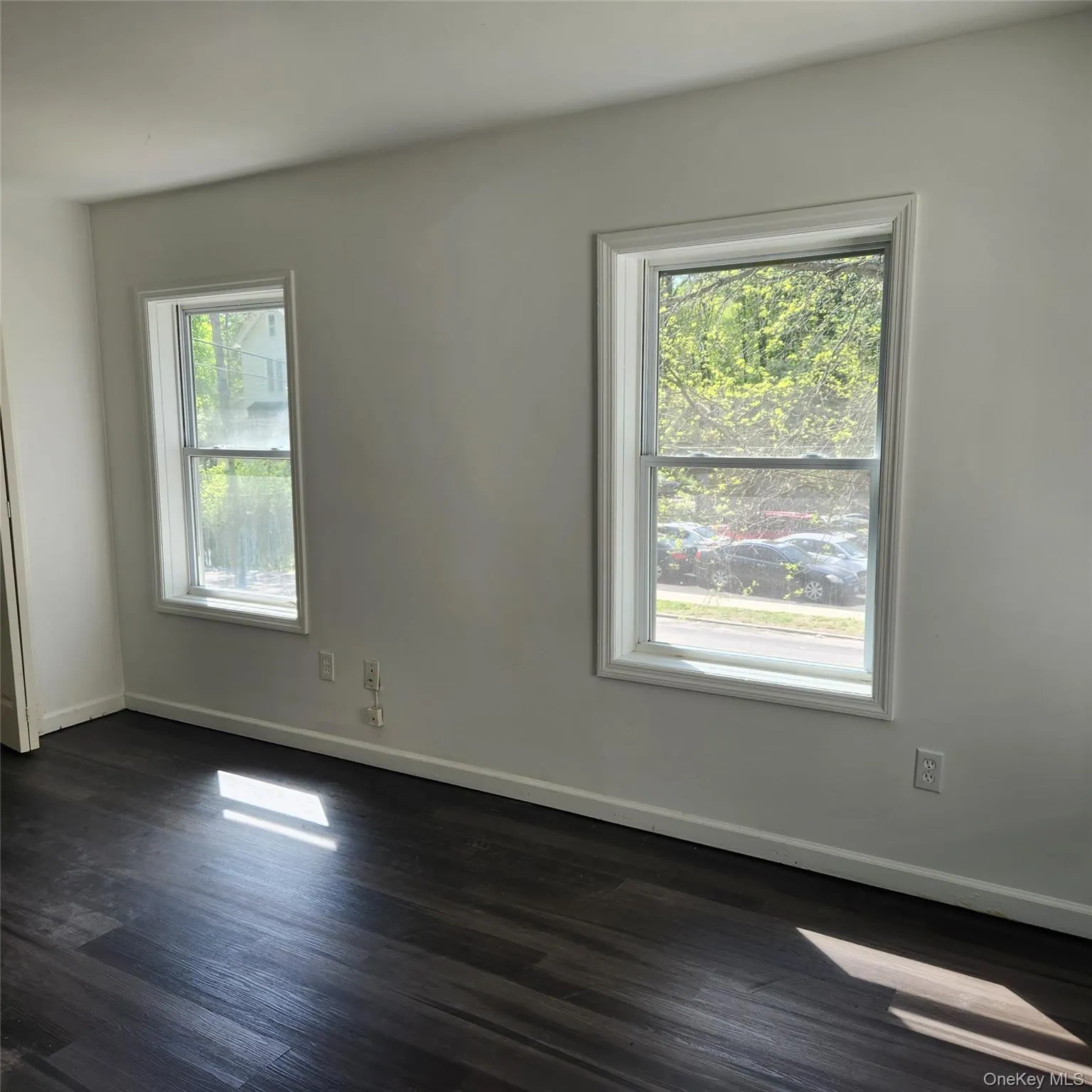 Unfurnished room with baseboards and dark wood-type flooring Unfurnished room with baseboards and dark wood-type flooring