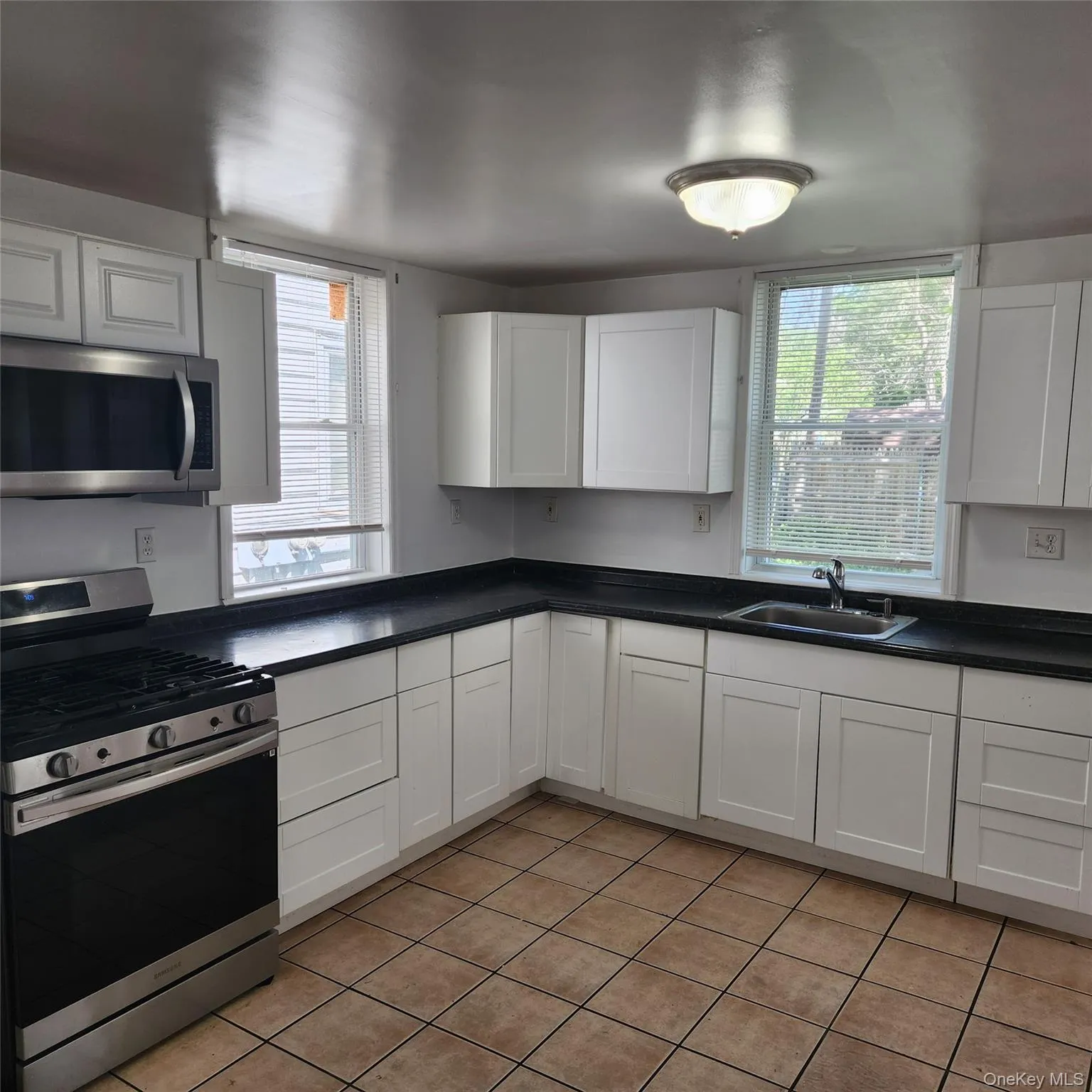 Kitchen with appliances with stainless steel finishes, white cabinetry, and dark countertops Kitchen with appliances with stainless steel finishes, white cabinetry, and dark countertops