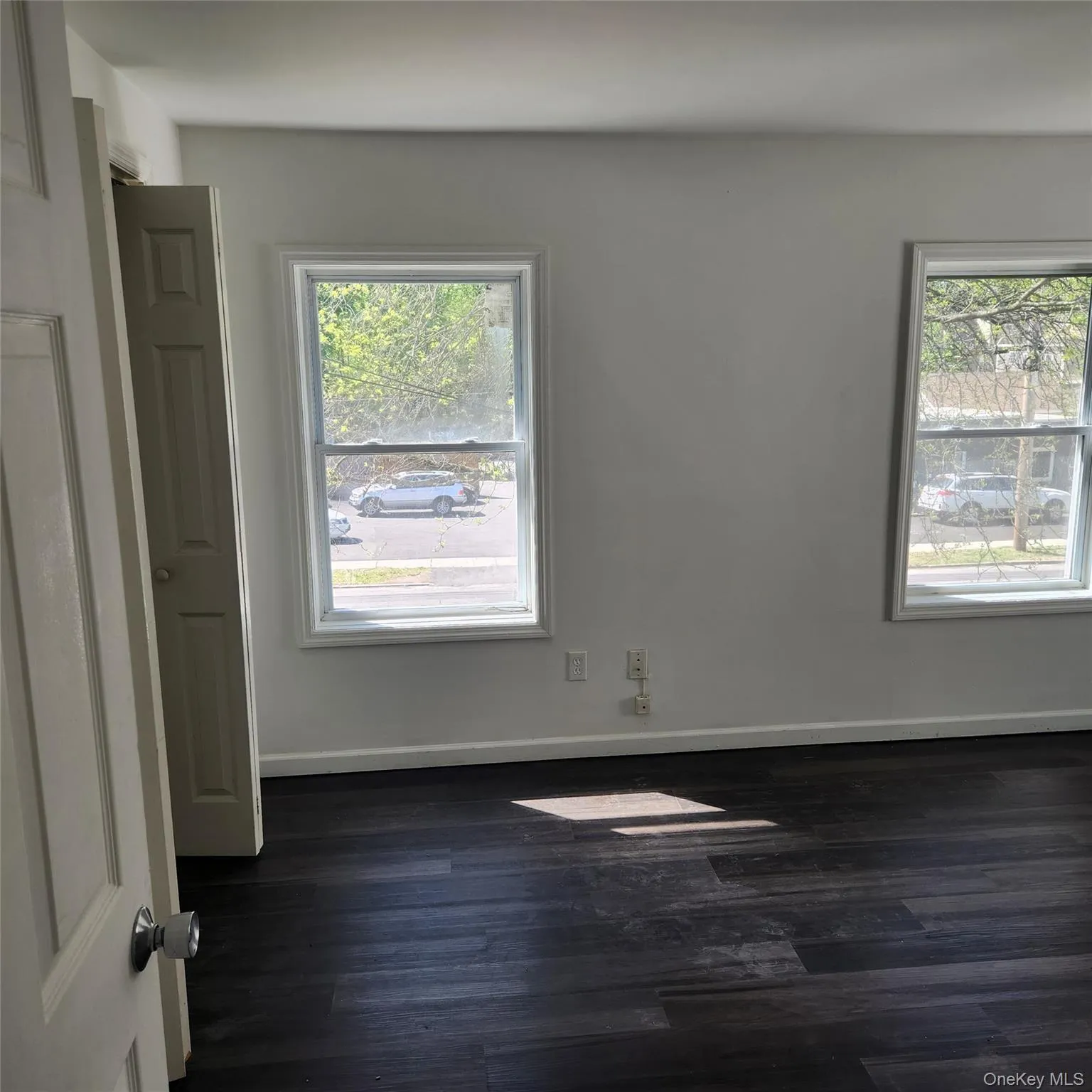 Empty room with baseboards and dark wood-style floors Empty room with baseboards and dark wood-style floors