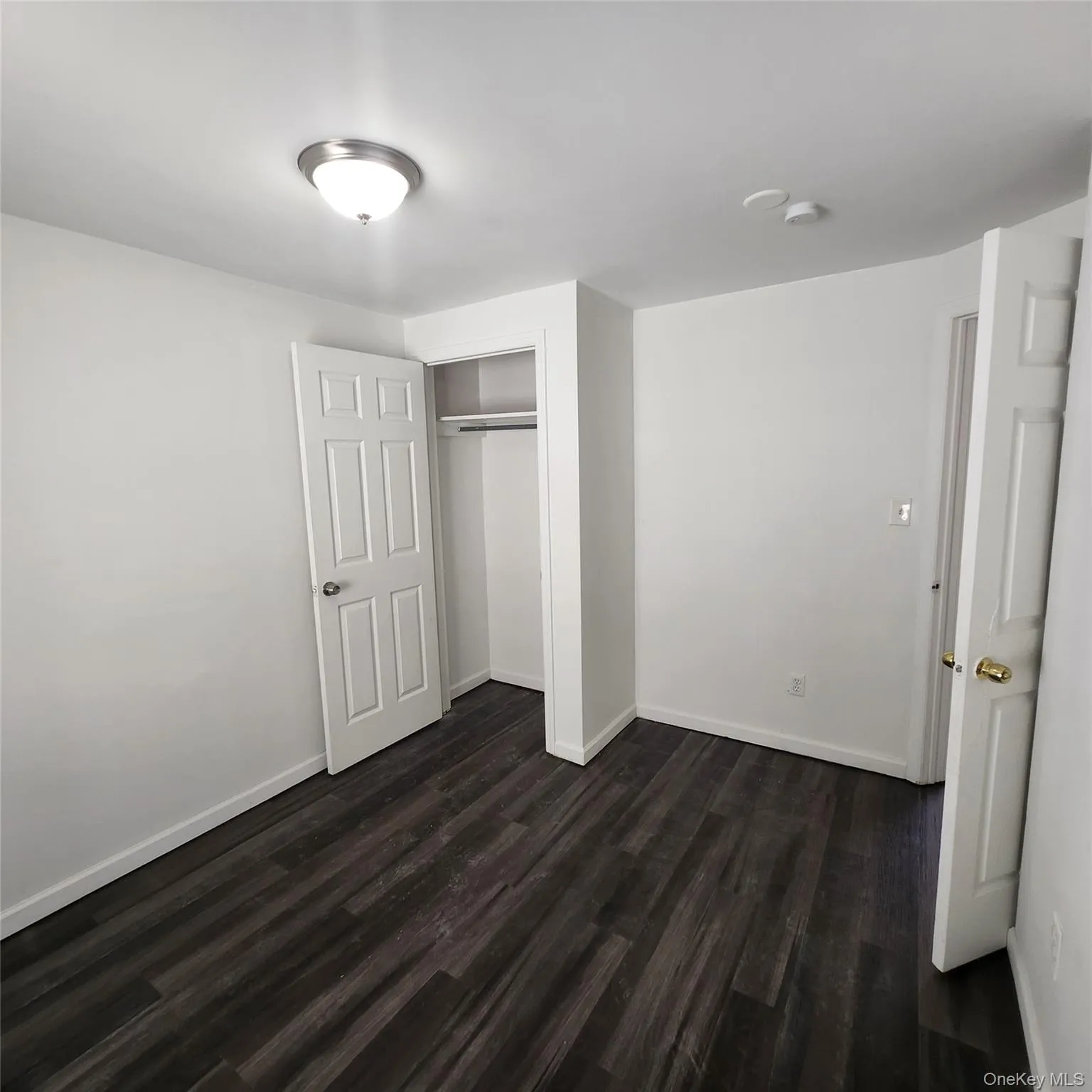 Unfurnished bedroom featuring dark wood-style floors and a closet Unfurnished bedroom featuring dark wood-style floors and a closet