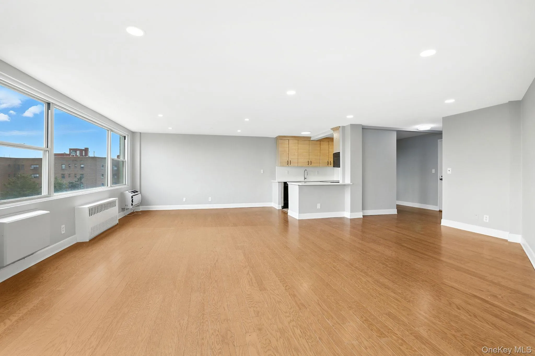 Unfurnished living room featuring radiator, light wood finished floors, and recessed lighting Unfurnished living room featuring radiator, light wood finished floors, and recessed lighting