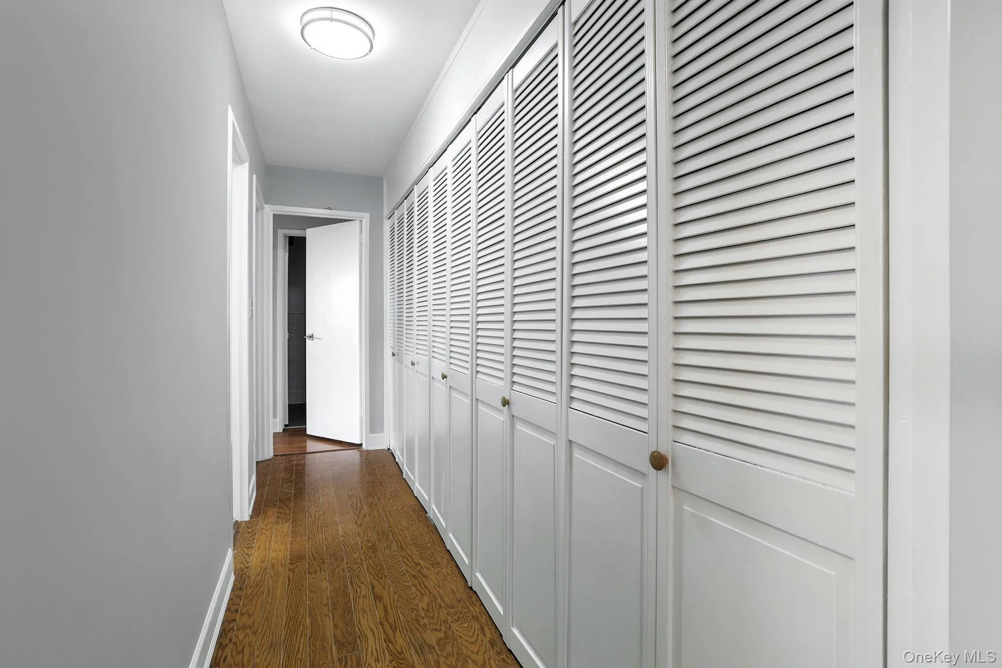 Hall to bedrooms and bathrooms featuring wood flooring and baseboards Hall to bedrooms and bathrooms featuring wood flooring and baseboards