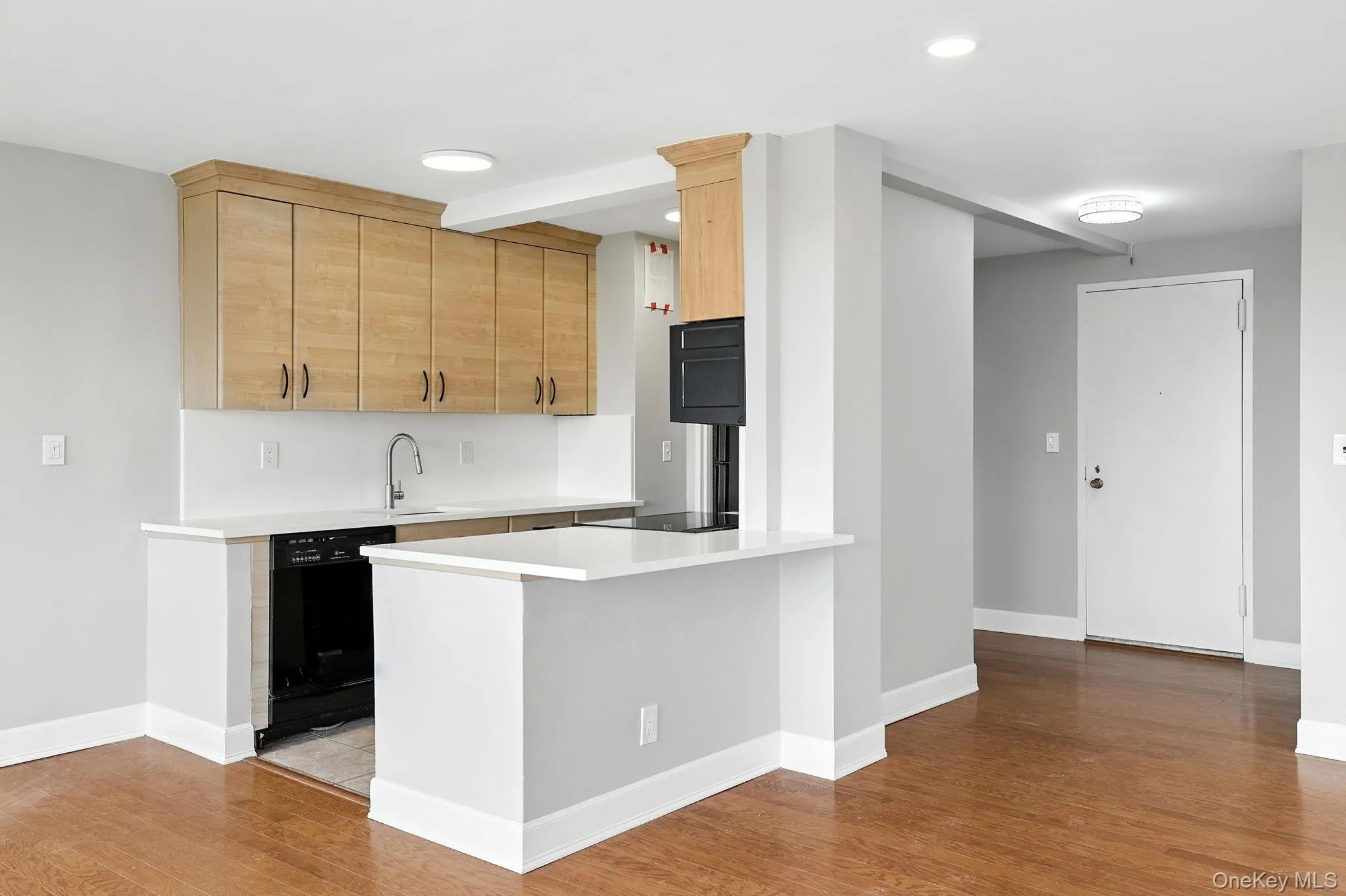 Kitchen with light brown cabinetry, wood flooring, black dishwasher, a peninsula, and recessed lighting Kitchen with light brown cabinetry, wood flooring, black dishwasher, a peninsula, and recessed lighting