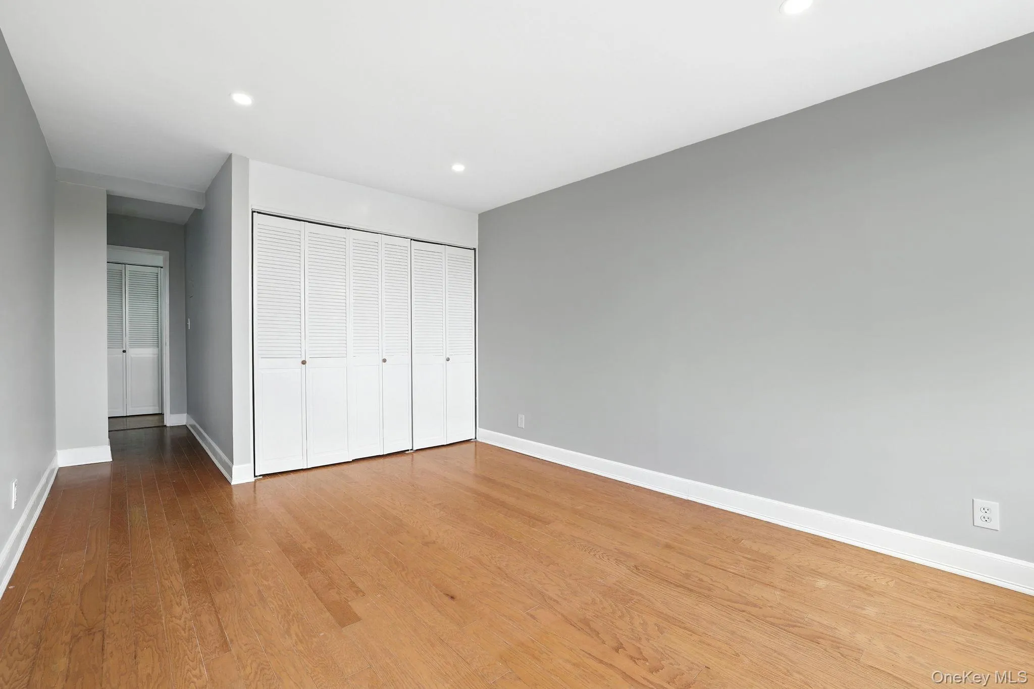 Unfurnished bedroom with wood finished floors, recessed lighting, and a large closet Unfurnished bedroom with wood finished floors, recessed lighting, and a large closet