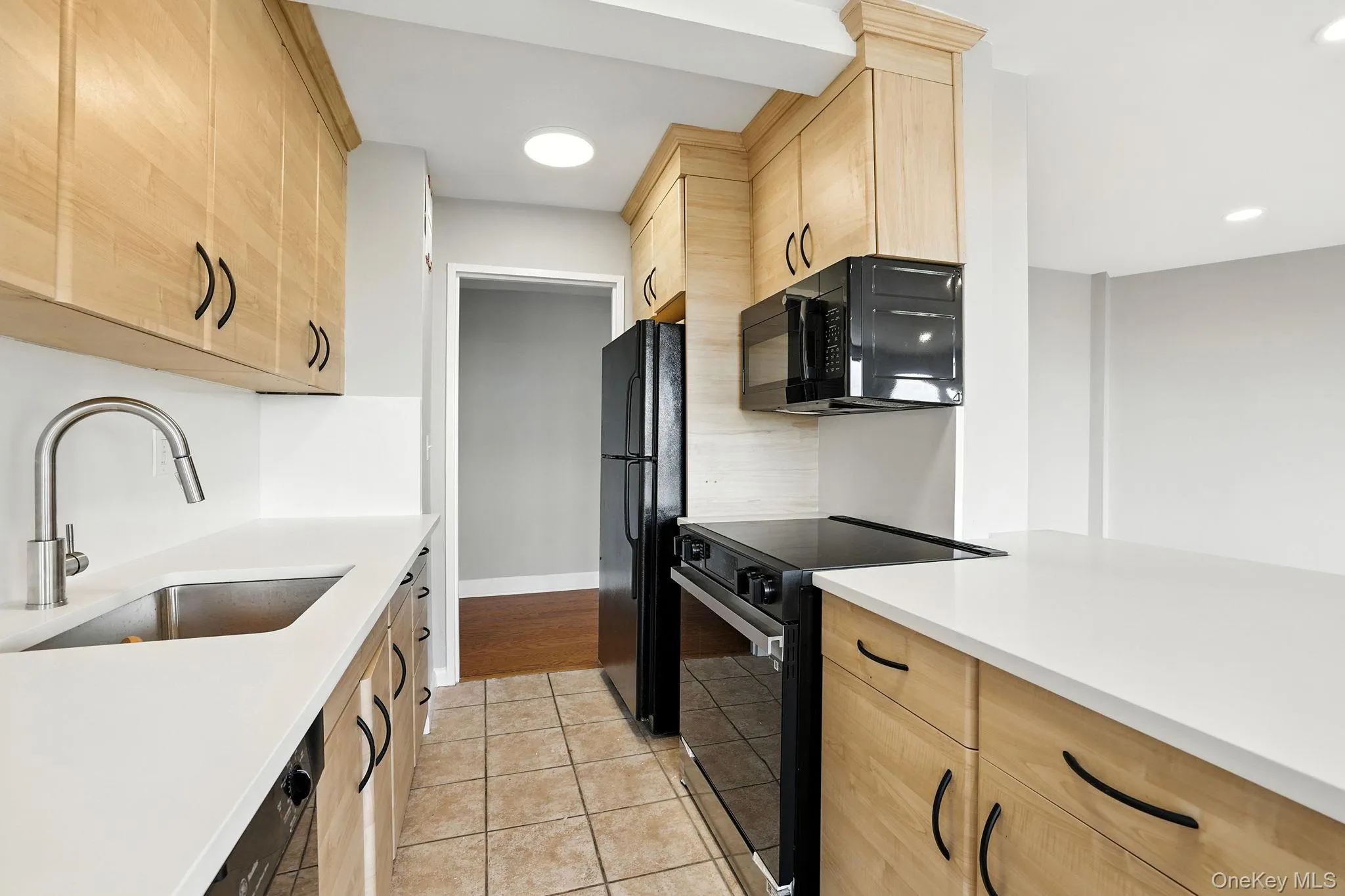 Kitchen featuring light brown cabinetry, black appliances, light tile patterned floors, and recessed lighting along with new quartz countertops Kitchen featuring light brown cabinetry, black appliances, light tile patterned floors, and recessed lighting along with new quartz countertops