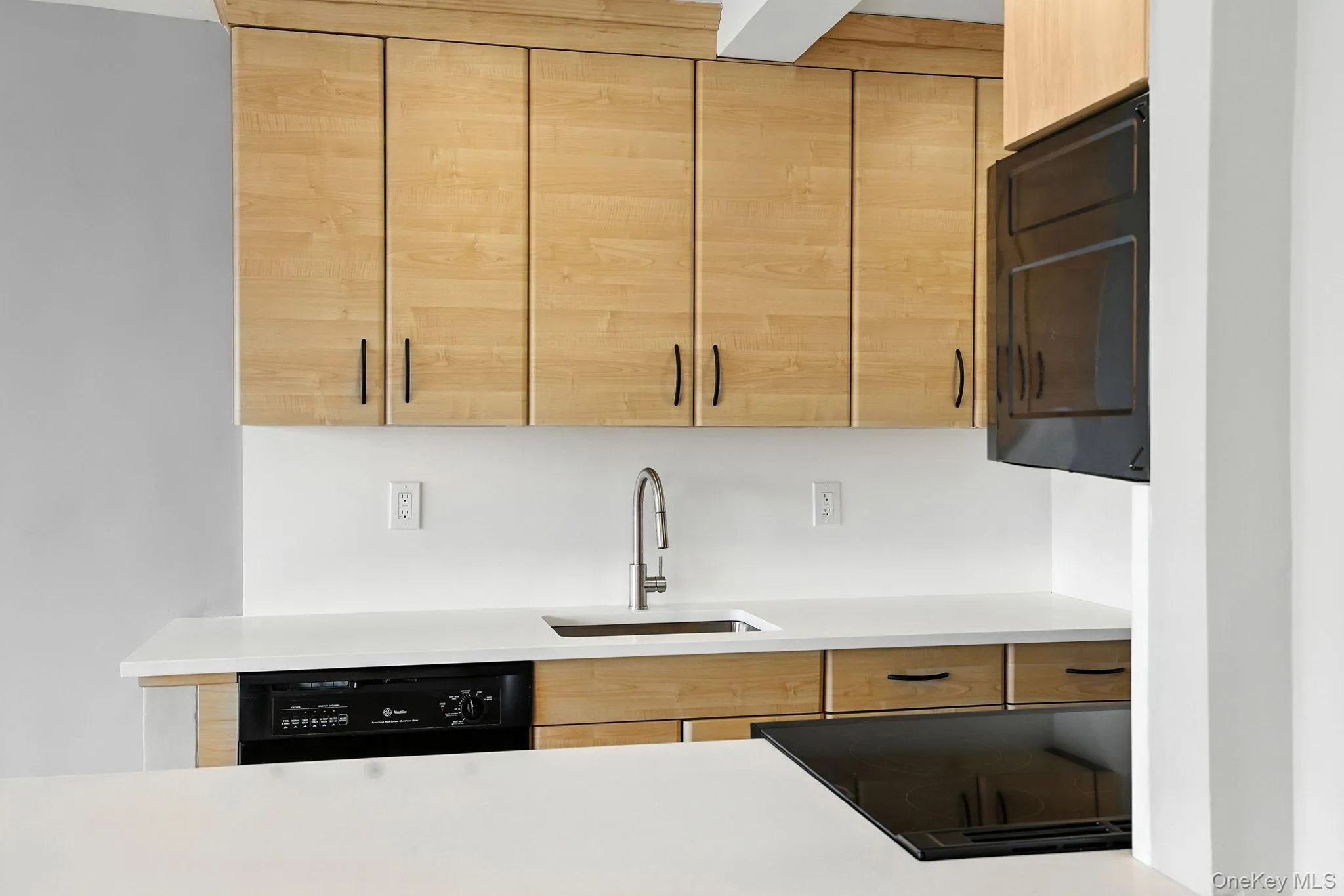 Kitchen with light brown, modern cabinets, black appliances, new quartz countertops Kitchen with light brown, modern cabinets, black appliances, new quartz countertops