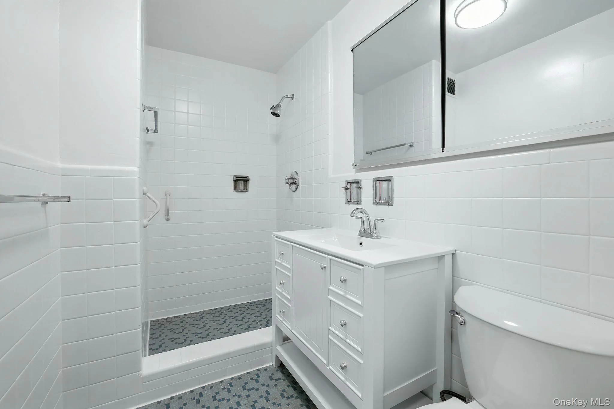 Primary full bathroom with tile walls, a shower stall, and vanity Primary full bathroom with tile walls, a shower stall, and vanity