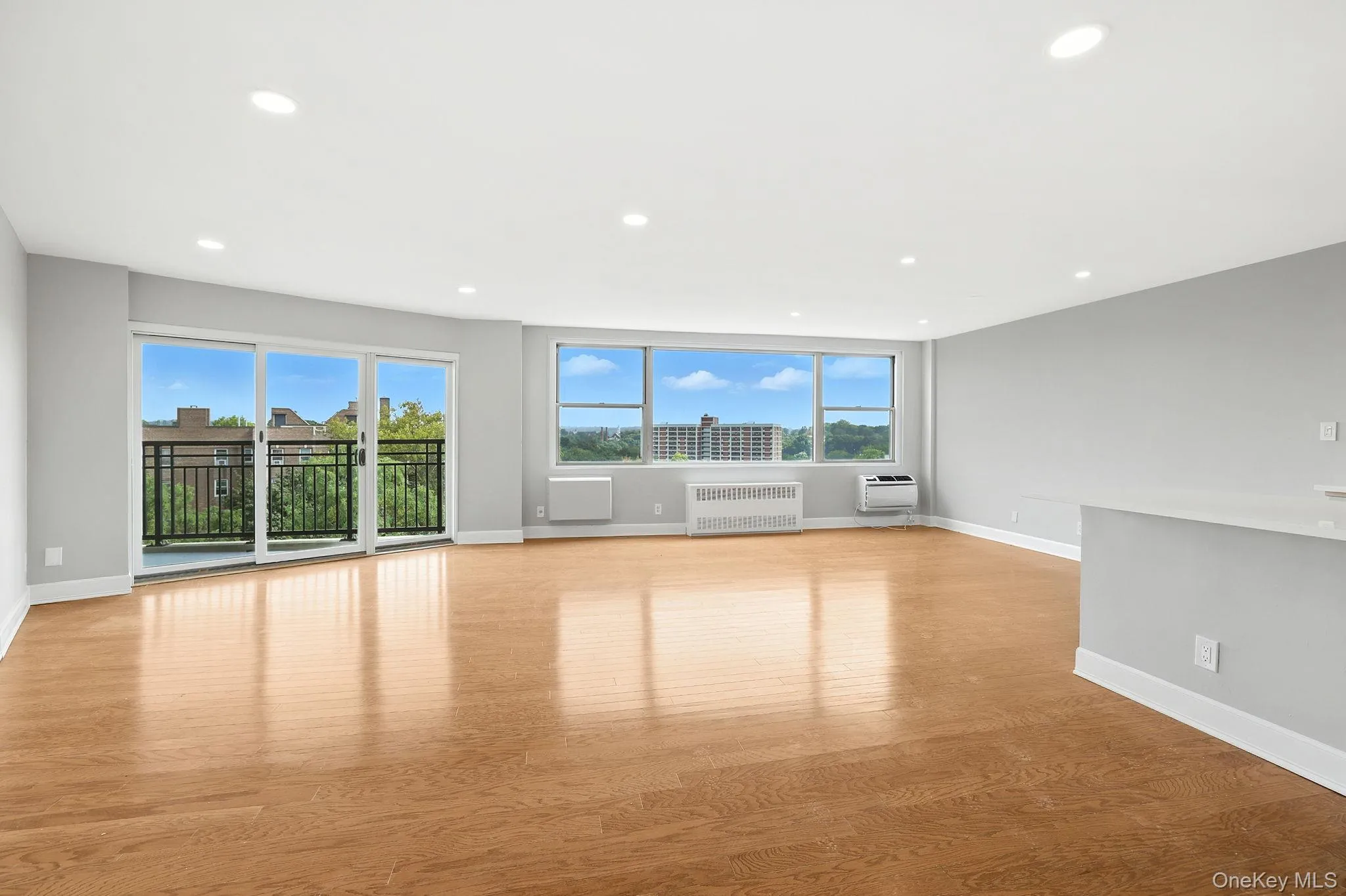 Unfurnished living room featuring light wood flooring, recessed lighting, and radiator Unfurnished living room featuring light wood flooring, recessed lighting, and radiator