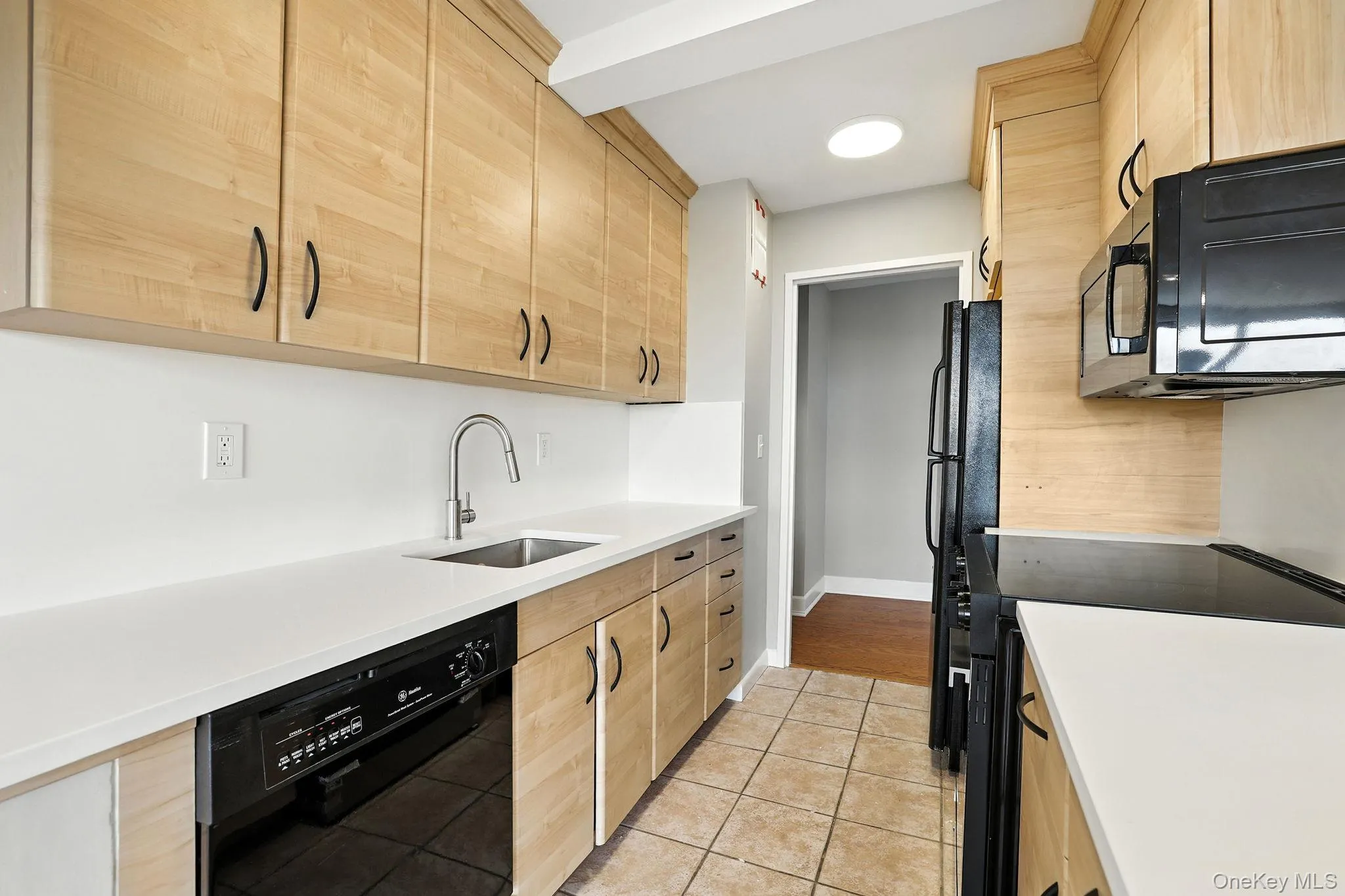 Kitchen featuring light brown cabinets, black appliances, light tile patterned floors, and new quartz counters Kitchen featuring light brown cabinets, black appliances, light tile patterned floors, and new quartz counters