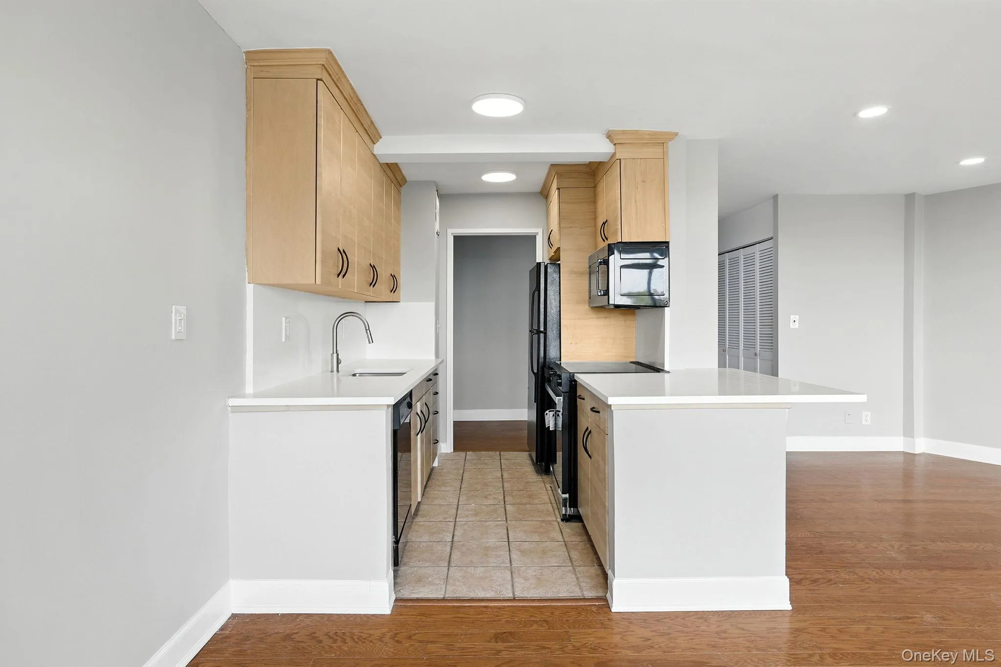 Kitchen with light brown cabinets, black appliances, light wood flooring, recessed lighting, and brand new quartz counters Kitchen with light brown cabinets, black appliances, light wood flooring, recessed lighting, and brand new quartz counters
