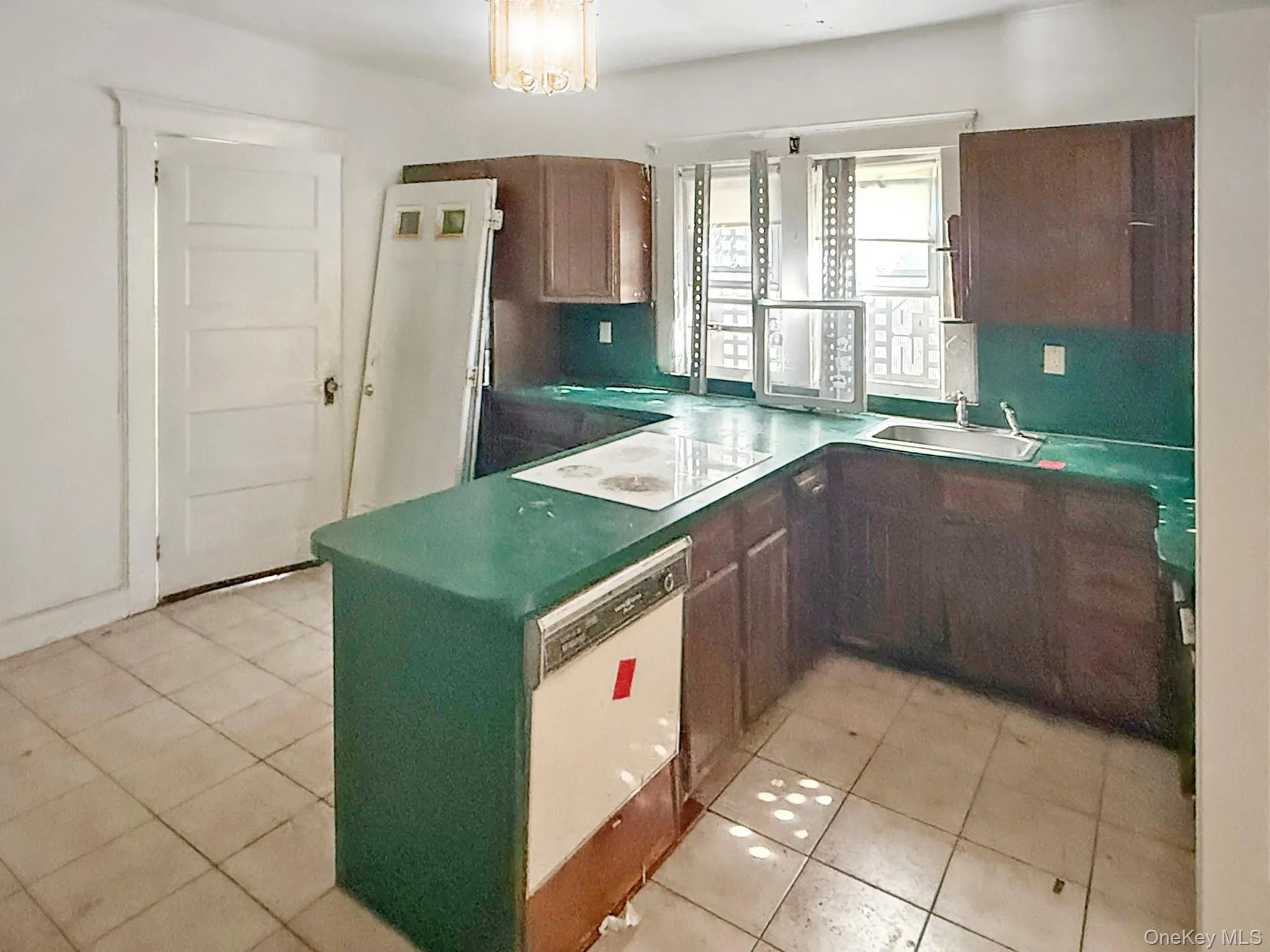 Kitchen with light tile patterned flooring, white appliances, a peninsula, and a chandelier Kitchen with light tile patterned flooring, white appliances, a peninsula, and a chandelier