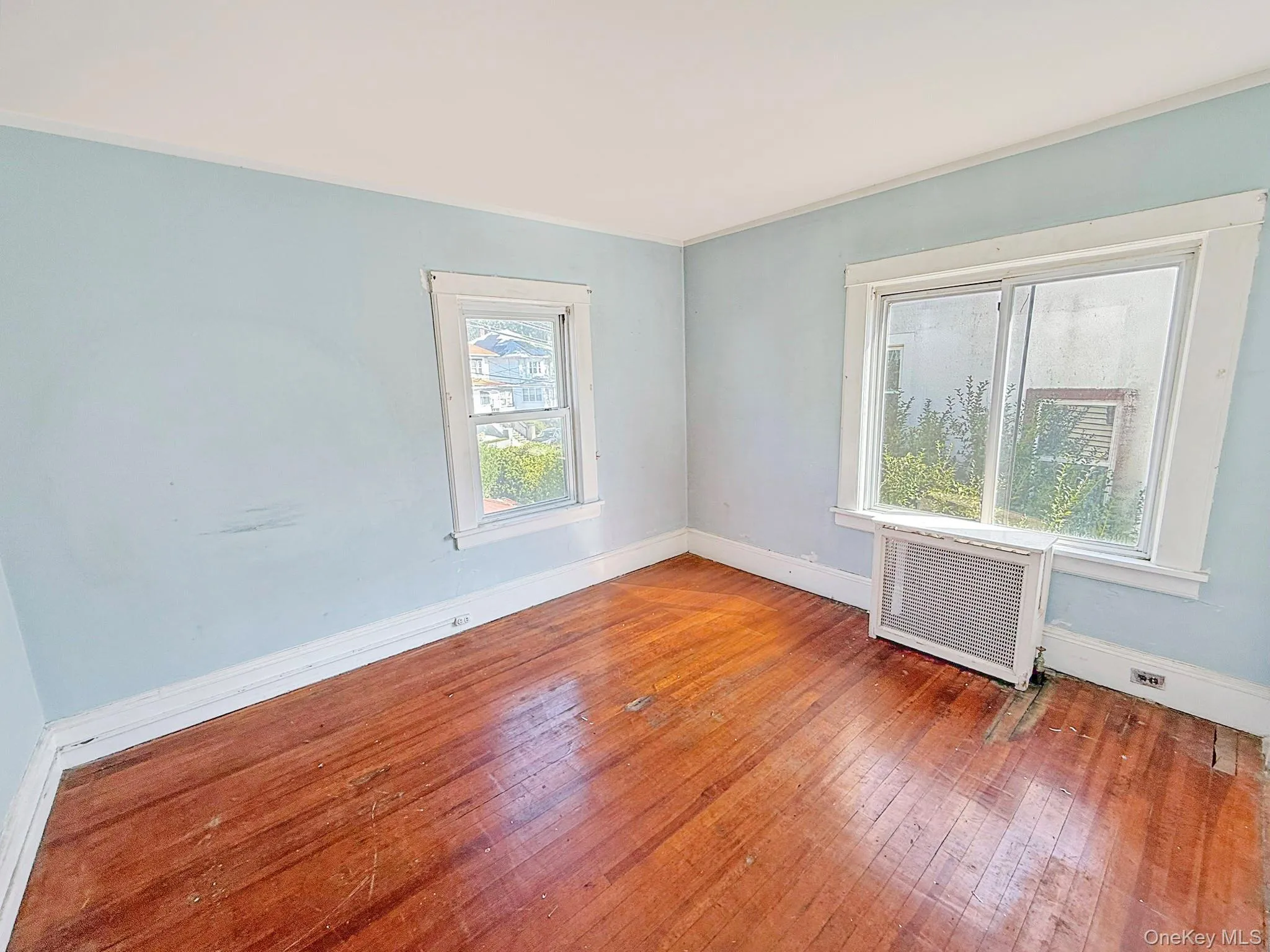 Spare room featuring wood-type flooring, radiator, and ornamental molding Spare room featuring wood-type flooring, radiator, and ornamental molding