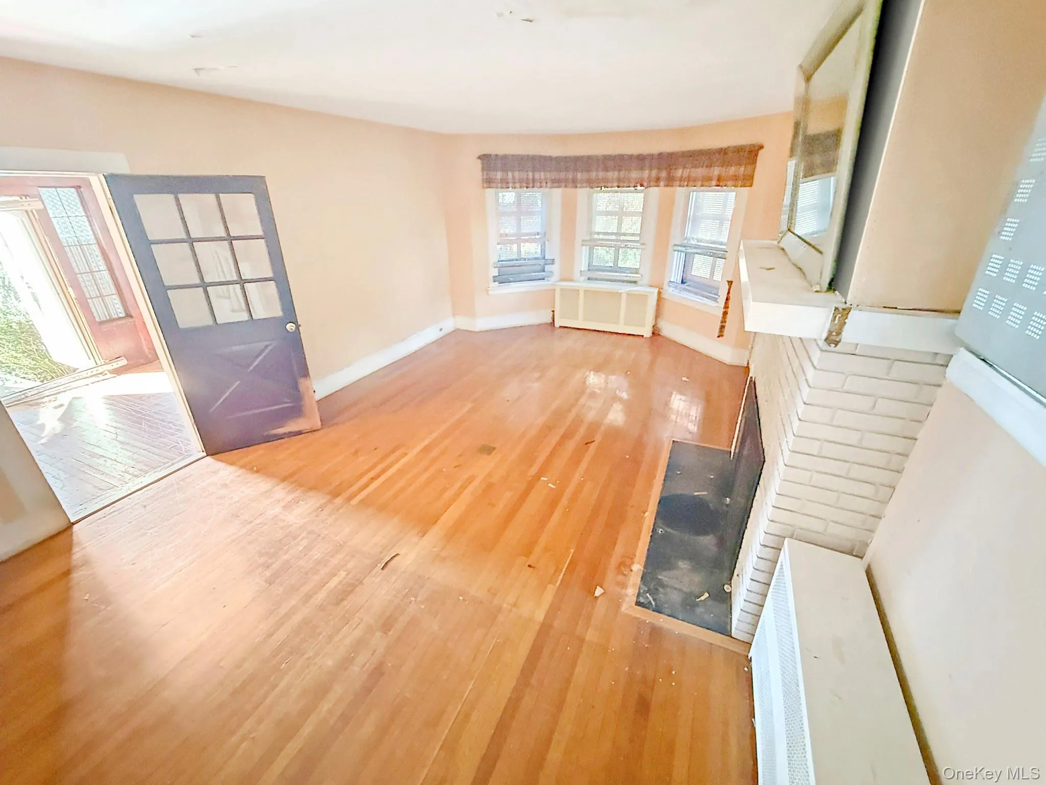 Unfurnished living room with wood finished floors and radiator heating unit Unfurnished living room with wood finished floors and radiator heating unit