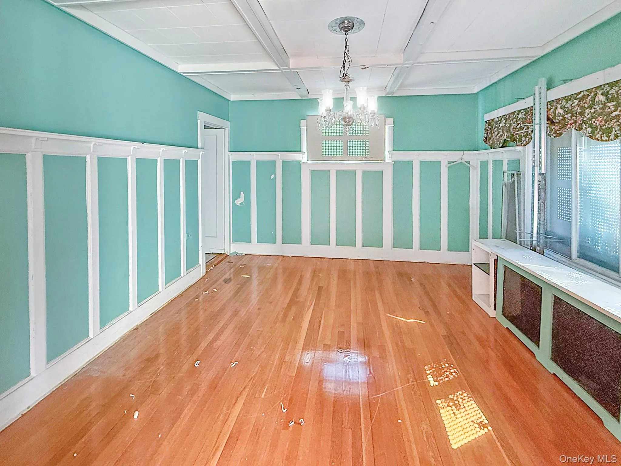 Unfurnished dining area with hardwood / wood-style flooring, a decorative wall, coffered ceiling, radiator, and a chandelier Unfurnished dining area with hardwood / wood-style flooring, a decorative wall, coffered ceiling, radiator, and a chandelier