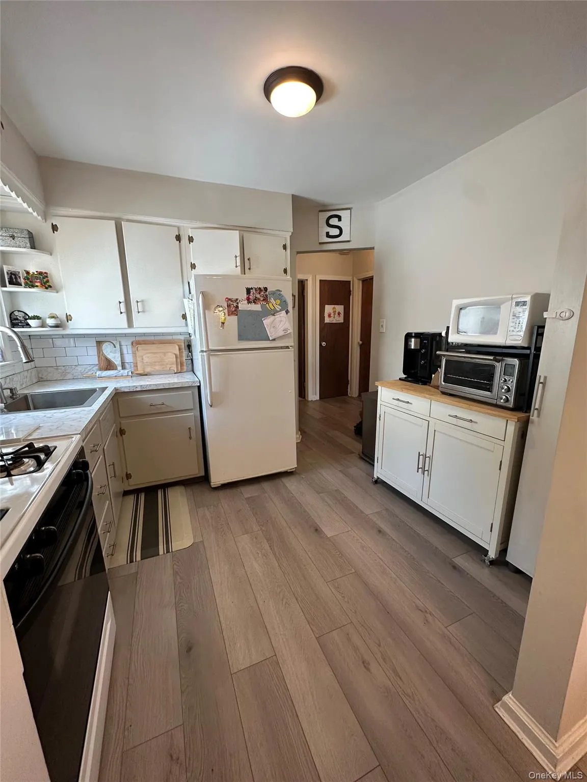 Kitchen with light countertops, white appliances, light wood-style floors, and white cabinetry Kitchen with light countertops, white appliances, light wood-style floors, and white cabinetry