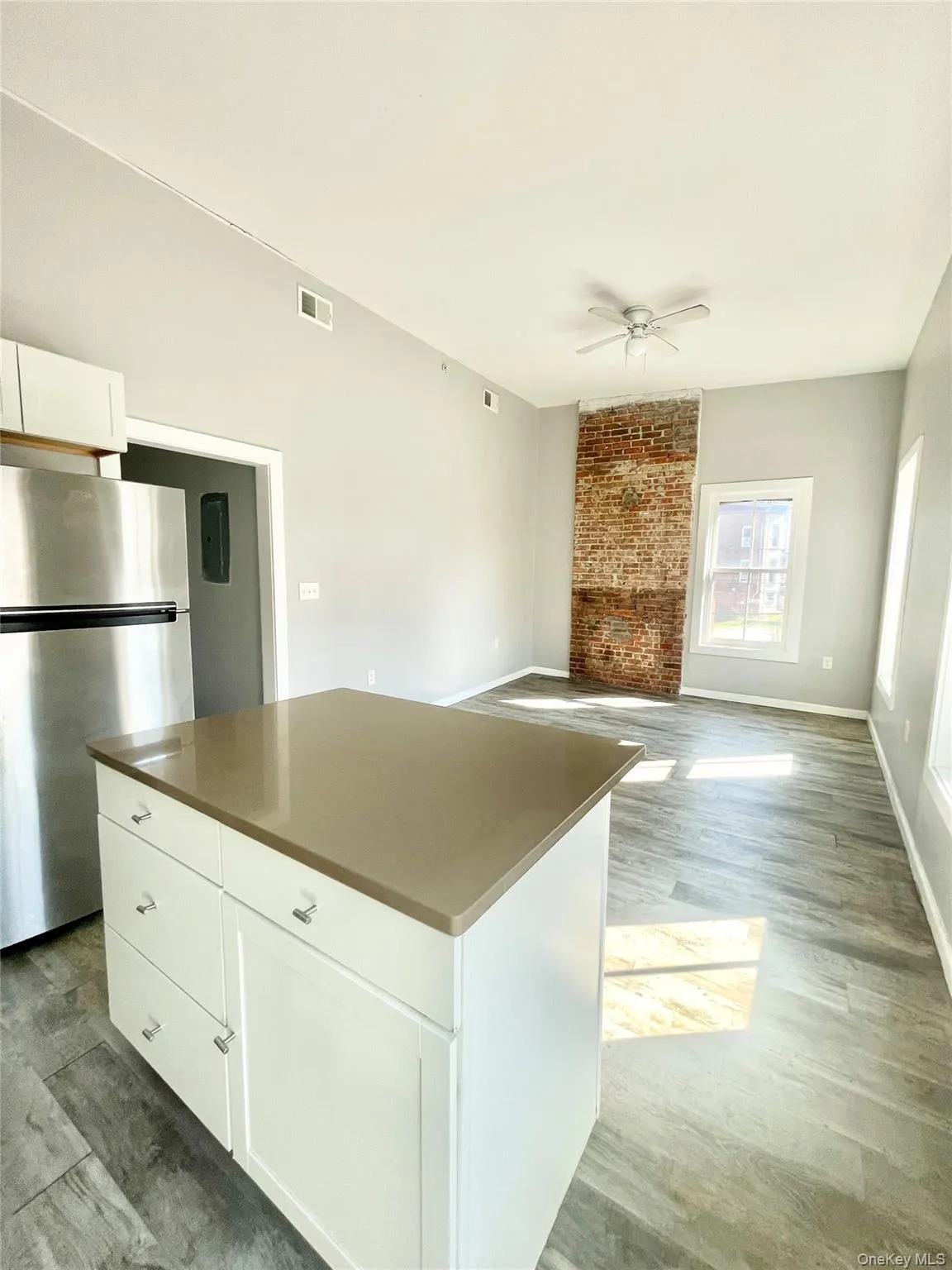 Kitchen featuring white cabinetry, freestanding refrigerator, light wood-type flooring, a center island, and open floor plan Kitchen featuring white cabinetry, freestanding refrigerator, light wood-type flooring, a center island, and open floor plan