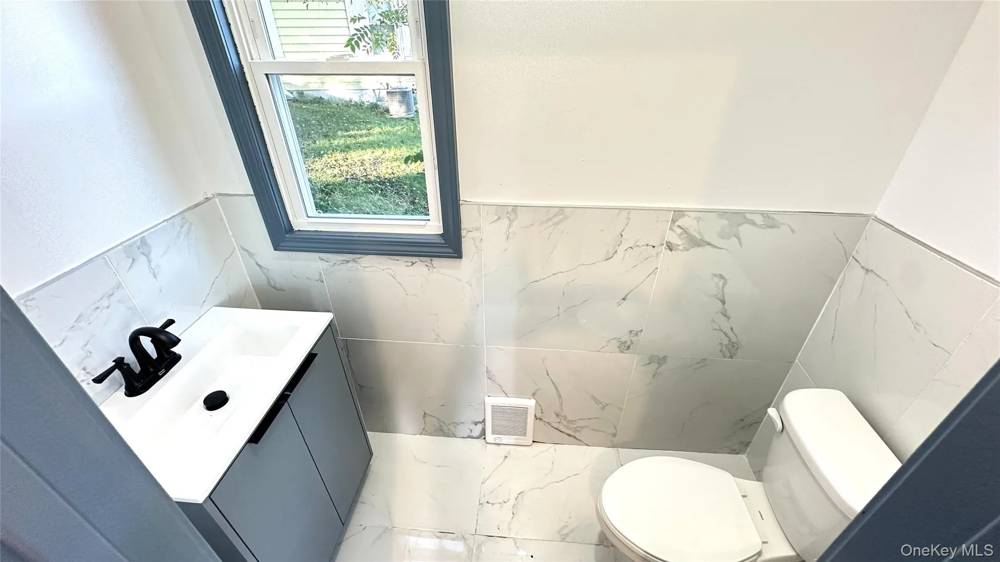 Bathroom featuring vanity, tile walls, wainscoting, and marble finish floors Bathroom featuring vanity, tile walls, wainscoting, and marble finish floors