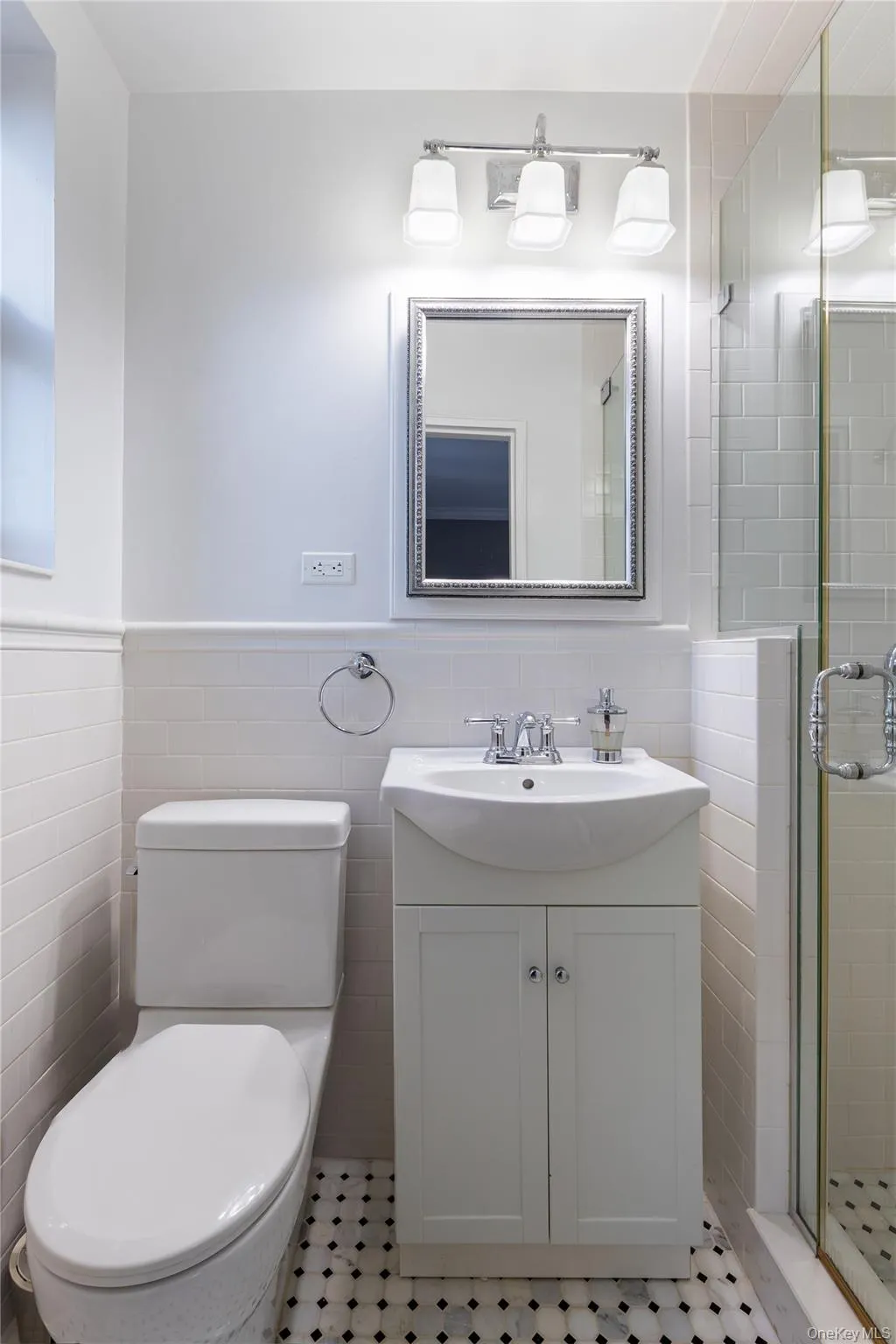 Full bath featuring tile walls, vanity, a shower stall, and wainscoting Full bath featuring tile walls, vanity, a shower stall, and wainscoting