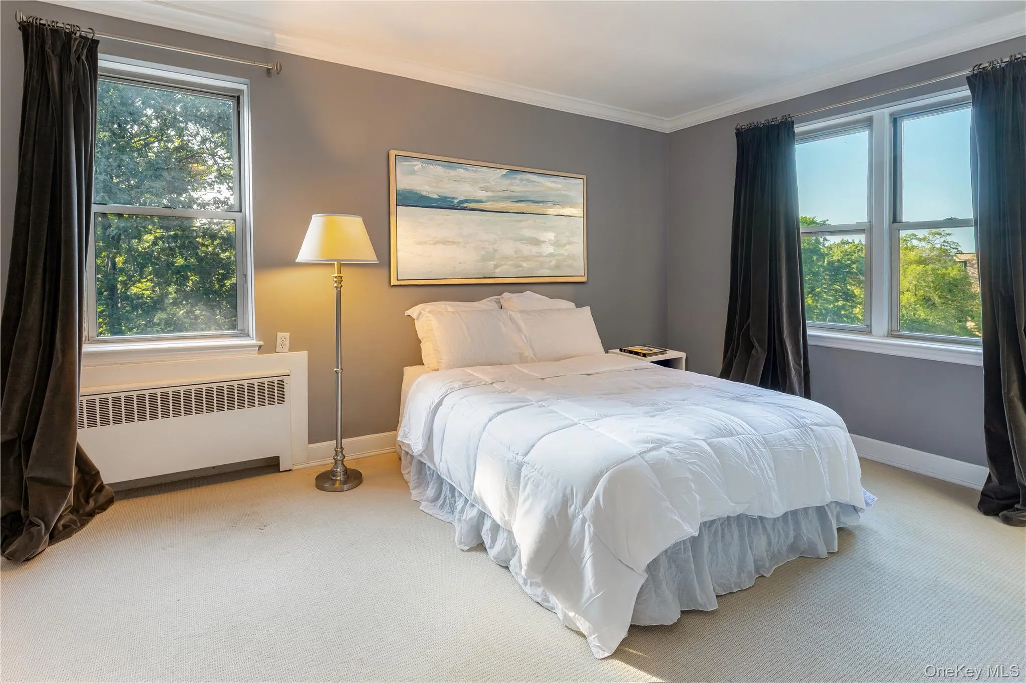 Carpeted bedroom featuring radiator heating unit, multiple windows, and crown molding Carpeted bedroom featuring radiator heating unit, multiple windows, and crown molding